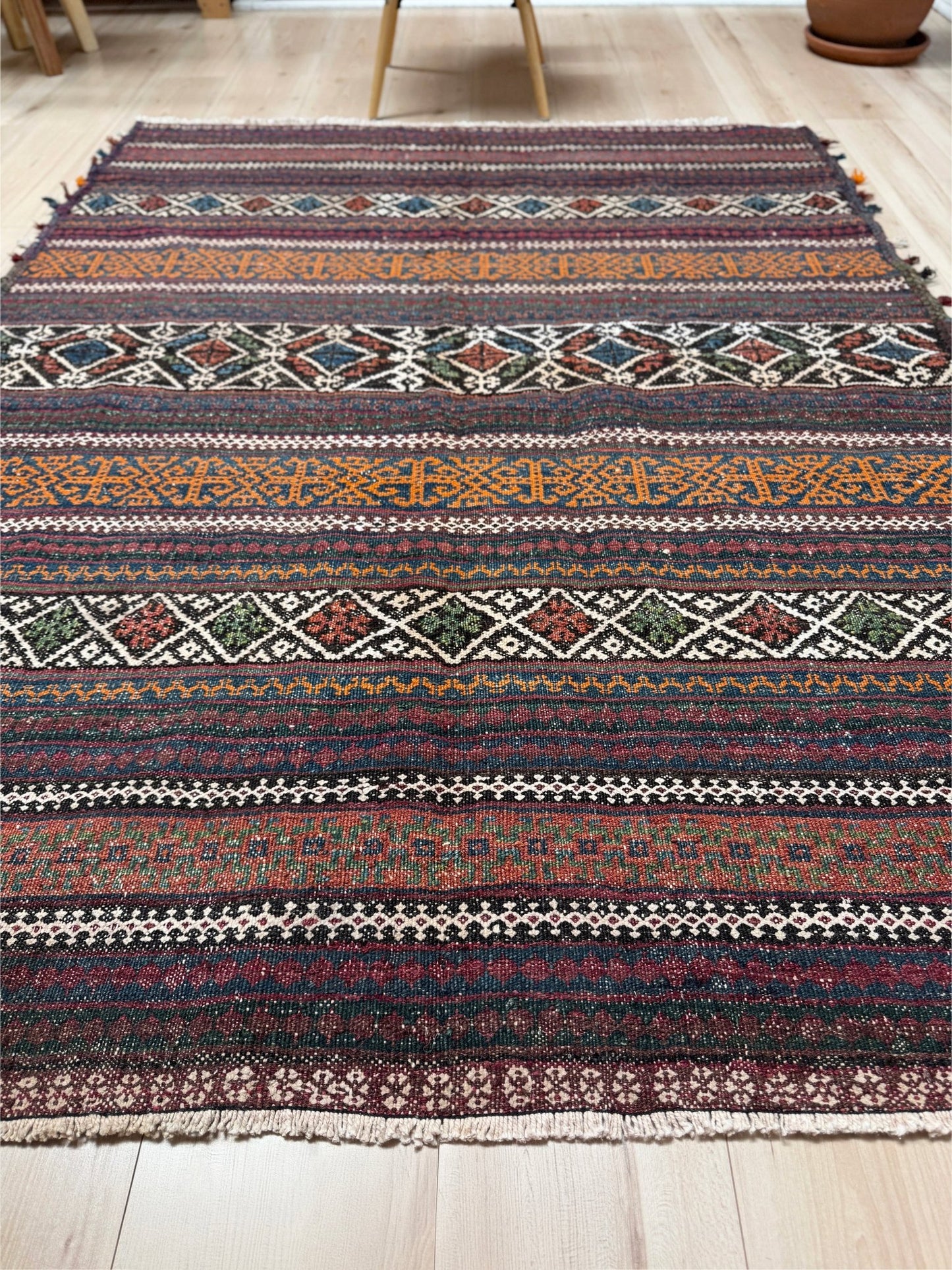Vintage Persian tribal kilim rug with geometric horizontal bands, brick red, indigo blue, orange, decorative side tassels, handmade wool flatweave 5x6 from Indigo Rugs Burlingame Bay Area.
