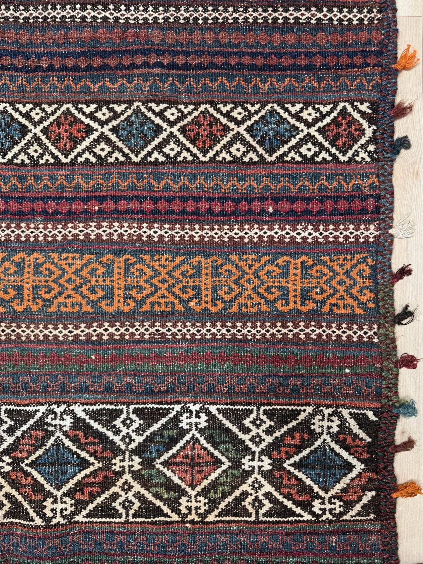 Vintage Persian tribal kilim rug with geometric horizontal bands, brick red, indigo blue, orange, decorative side tassels, handmade wool flatweave 5x6 from Indigo Rugs Burlingame Bay Area.
