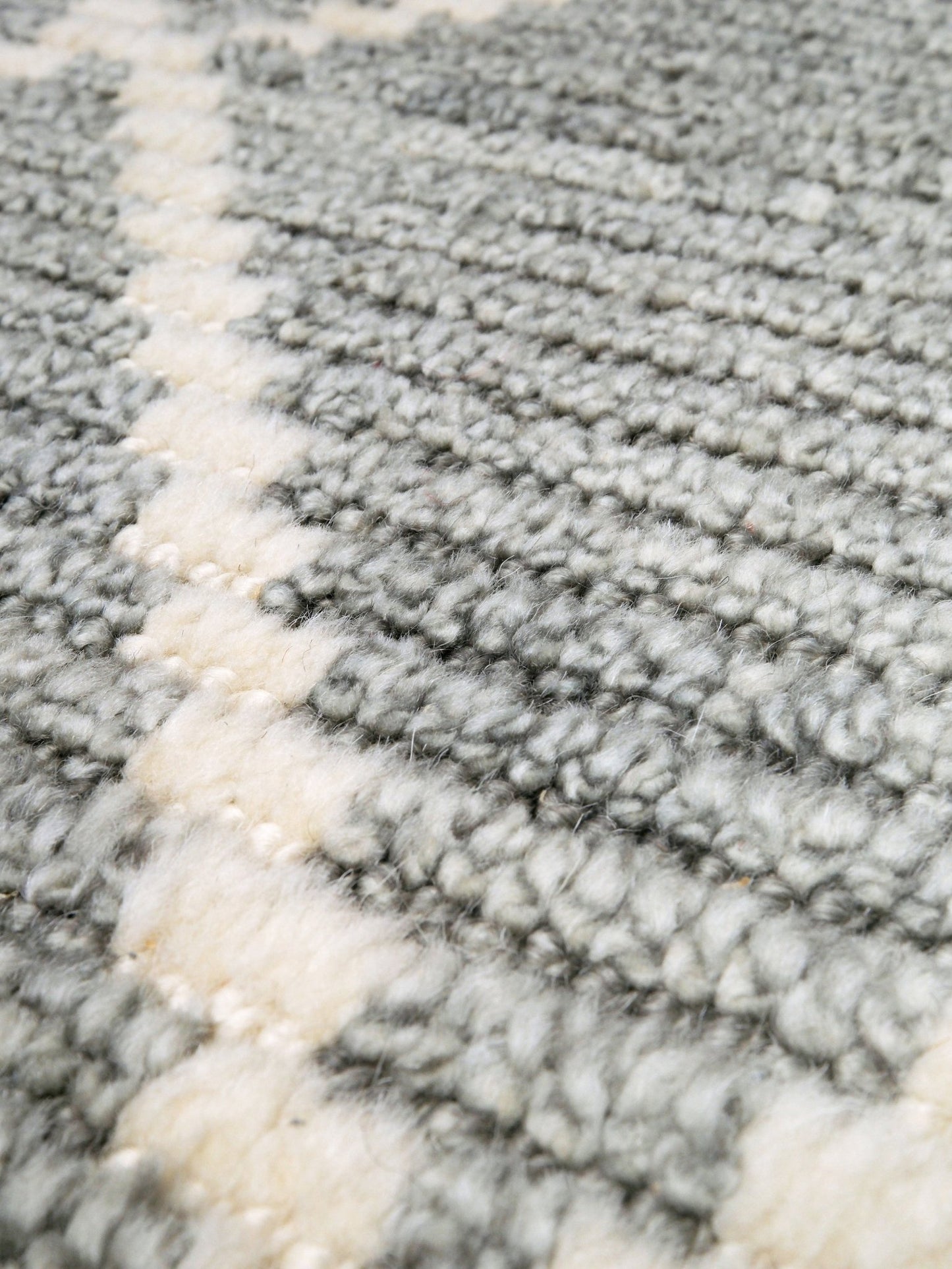 Close-up of a textured gray and white rug. Small gray Turkish Tulu rug with ivory geometric diamond pattern, handmade wool rug, 4x6 from Indigo Rugs Burlingame Bay Area.