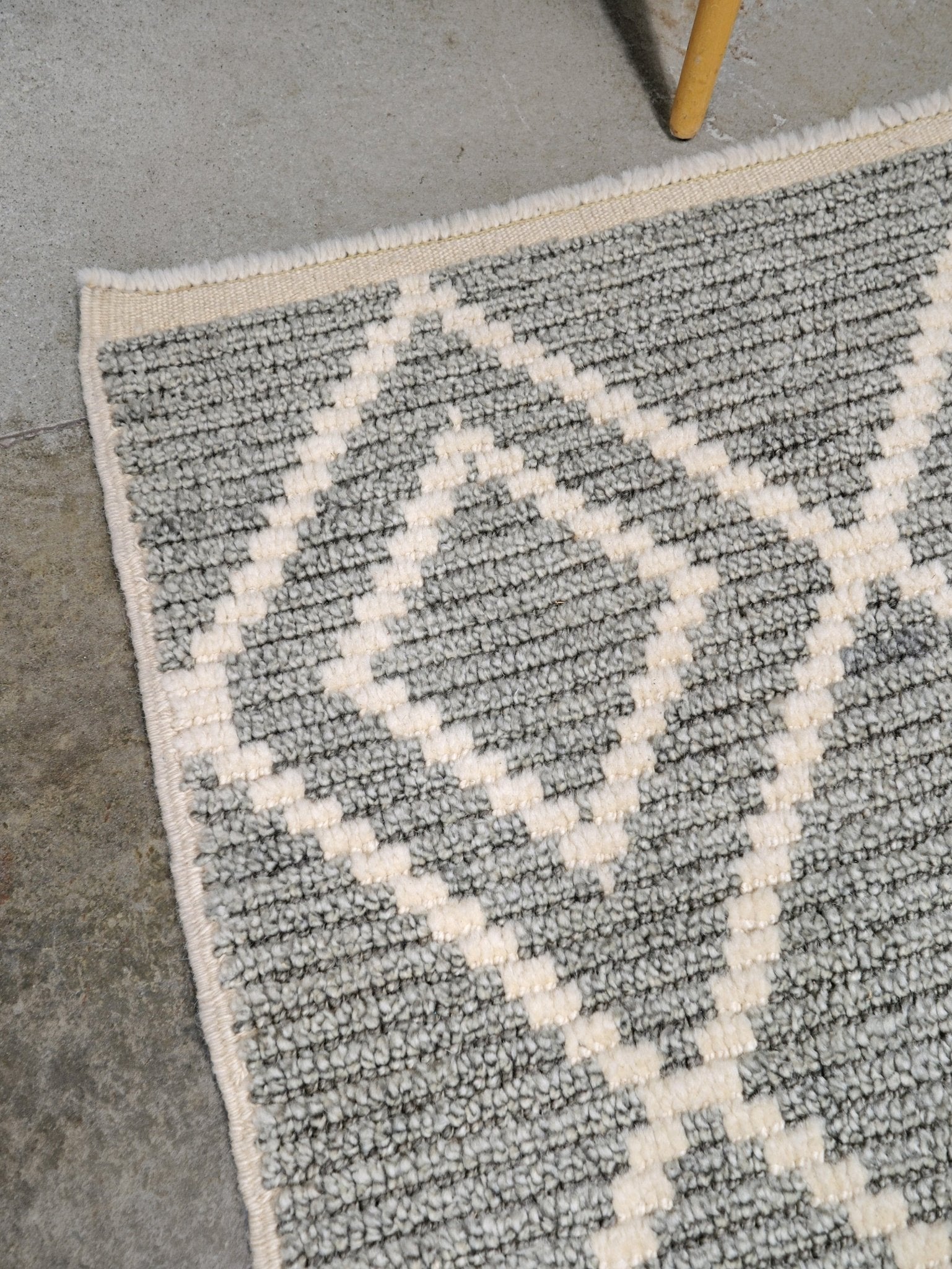 Close-up of a gray and white geometric patterned rug. Small gray Turkish Tulu rug with ivory diamond pattern, handmade wool rug, 4x6 from Indigo Rugs Burlingame Bay Area.