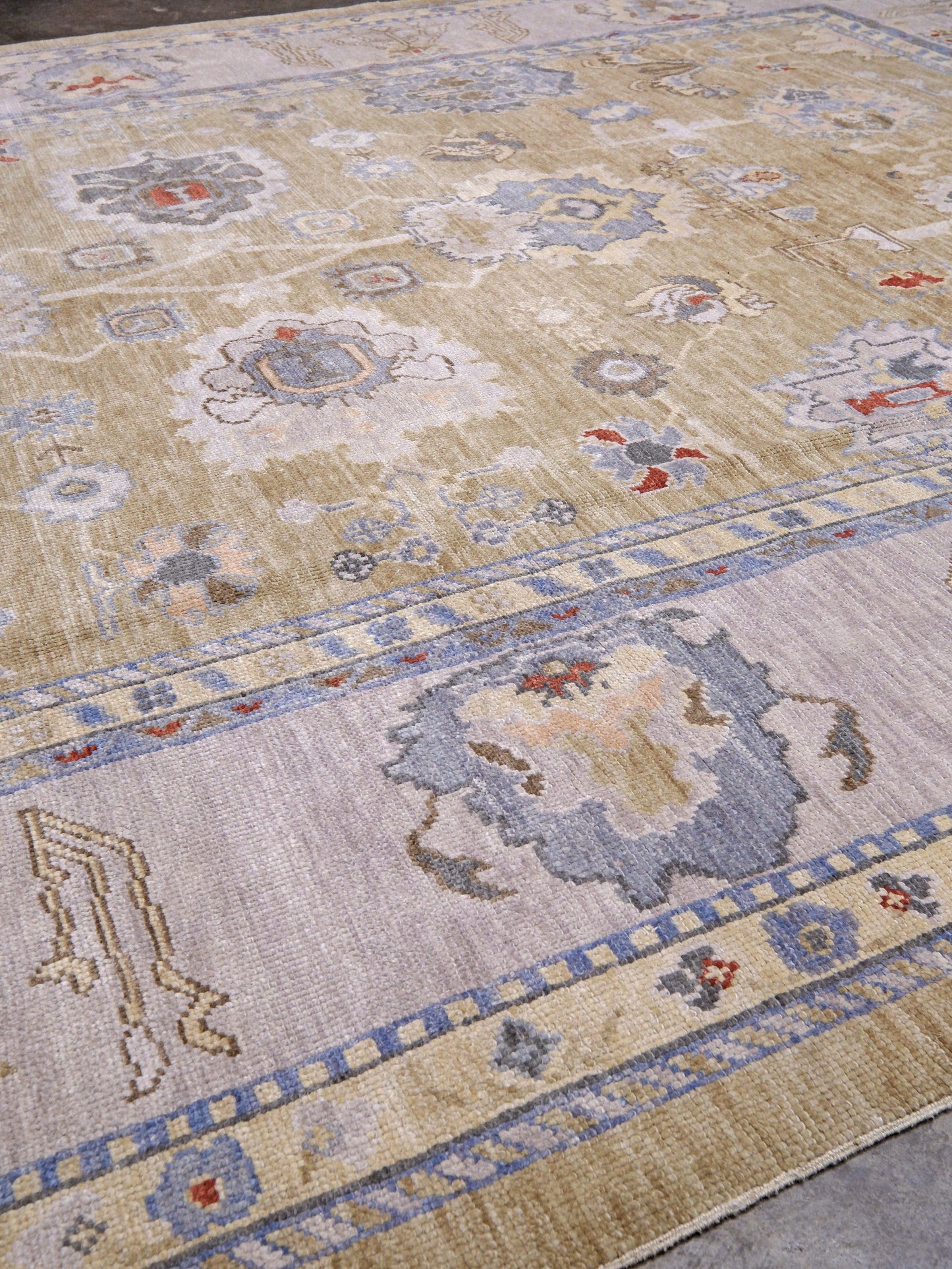 Light olive Turkish Oushak rug with warm ivory border, powder blue floral motifs, soft gray, taupe, and rust accents, hand-knotted wool 10x14 area rug from Indigo Rugs Burlingame Bay Area.
