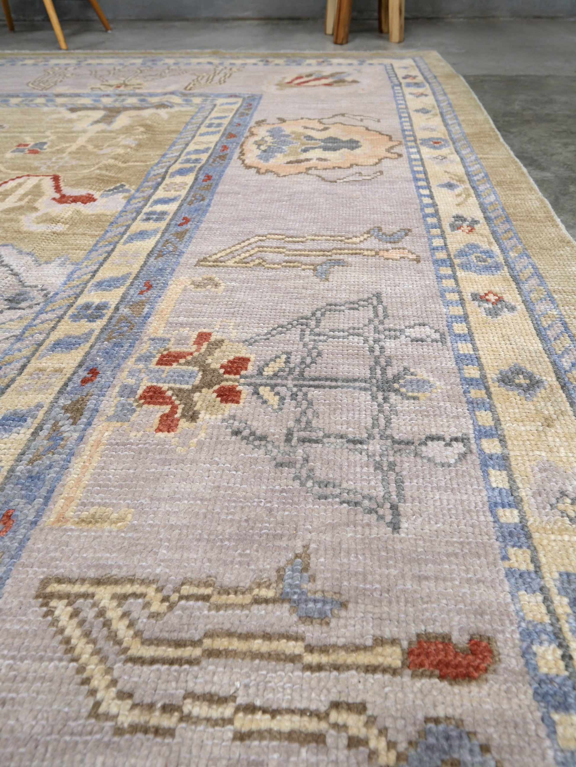 Light olive Turkish Oushak rug with warm ivory border, powder blue floral motifs, soft gray, taupe, and rust accents, hand-knotted wool 10x14 area rug from Indigo Rugs Burlingame Bay Area.