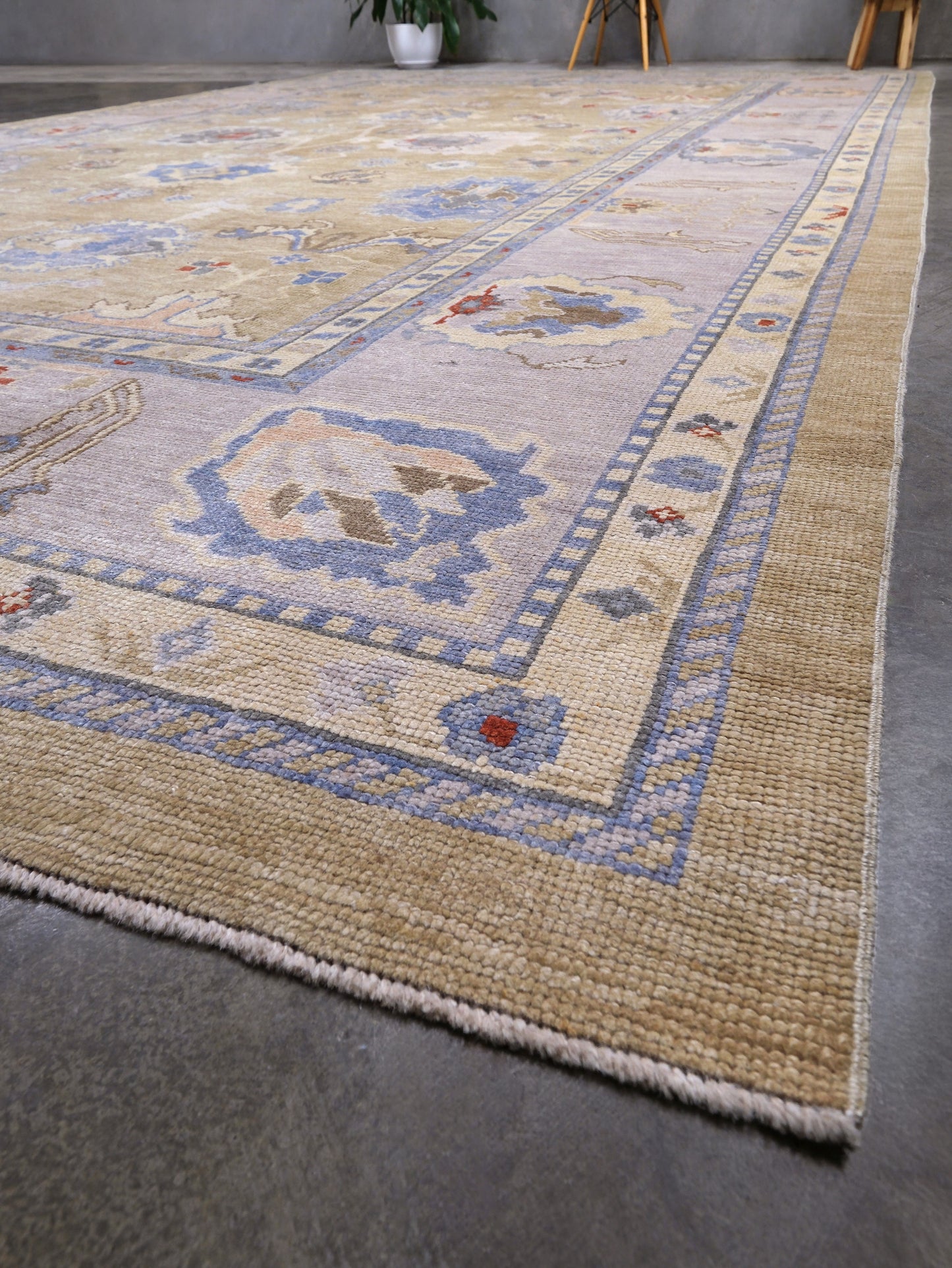 Light olive Turkish Oushak rug with warm ivory border, powder blue floral motifs, soft gray, taupe, and rust accents, hand-knotted wool 10x14 area rug from Indigo Rugs Burlingame Bay Area.