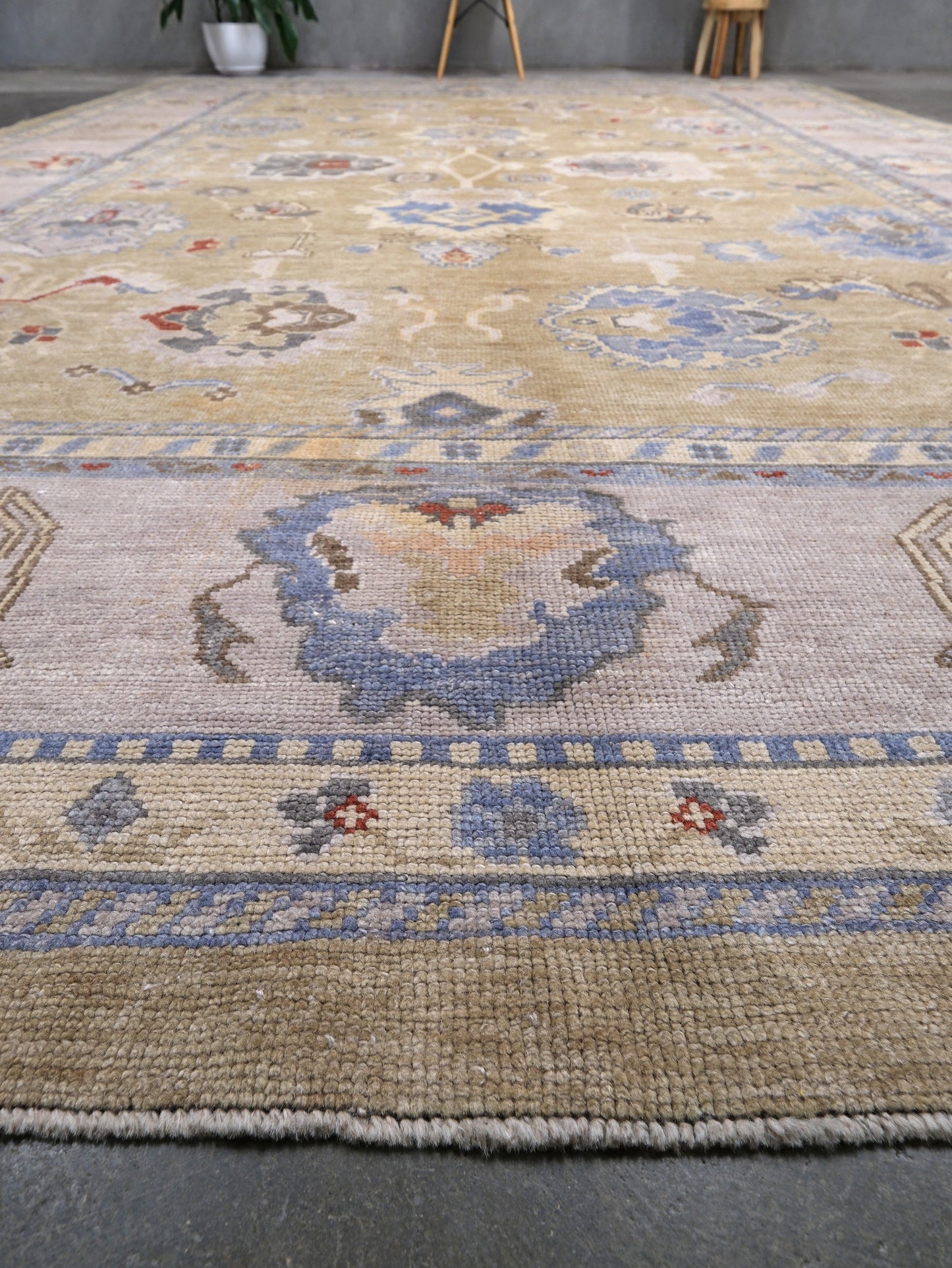 Light olive Turkish Oushak rug with warm ivory border, powder blue floral motifs, soft gray, taupe, and rust accents, hand-knotted wool 10x14 area rug from Indigo Rugs Burlingame Bay Area.