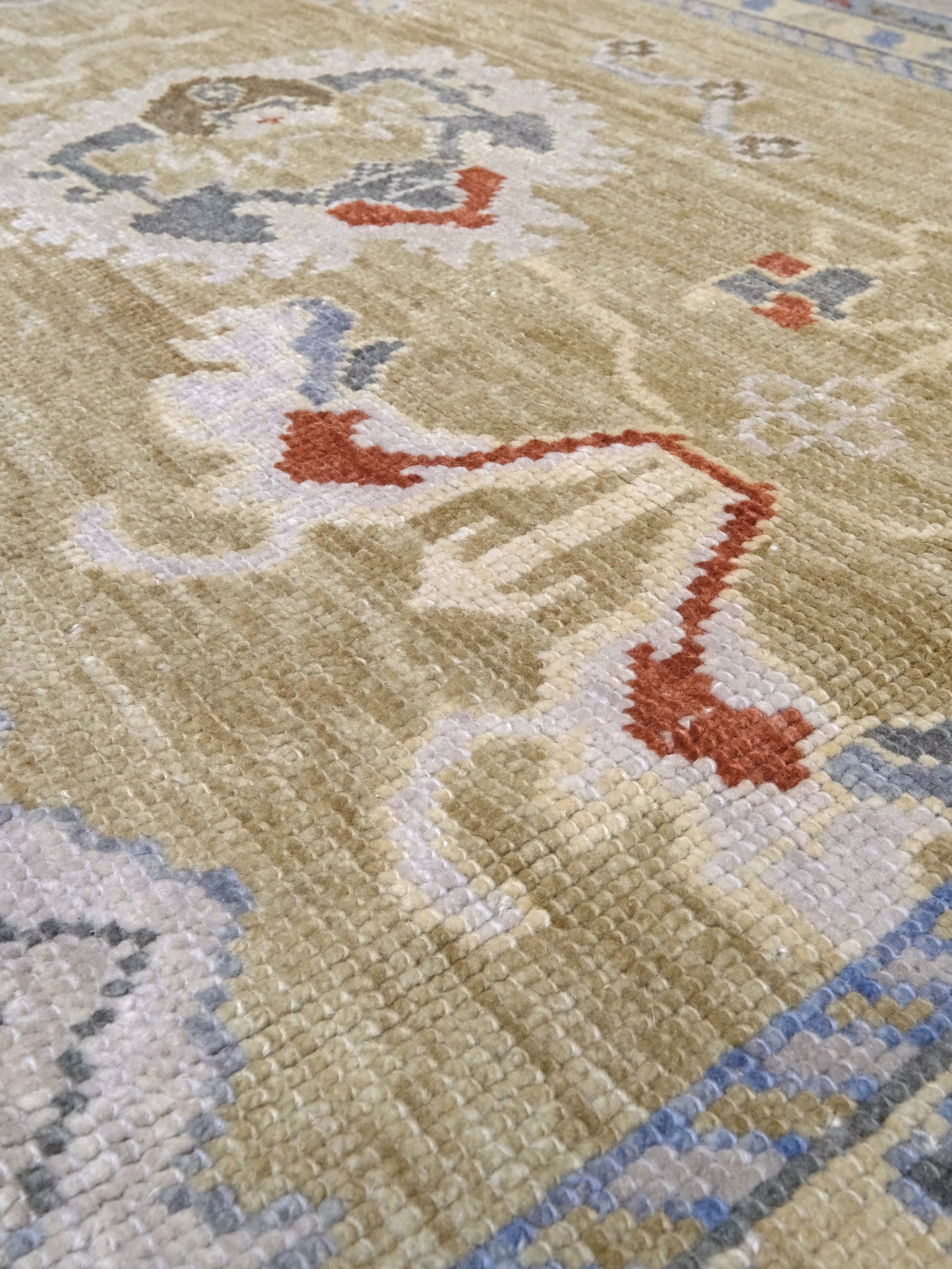 Light olive Turkish Oushak rug with warm ivory border, powder blue floral motifs, soft gray, taupe, and rust accents, hand-knotted wool 10x14 area rug from Indigo Rugs Burlingame Bay Area.