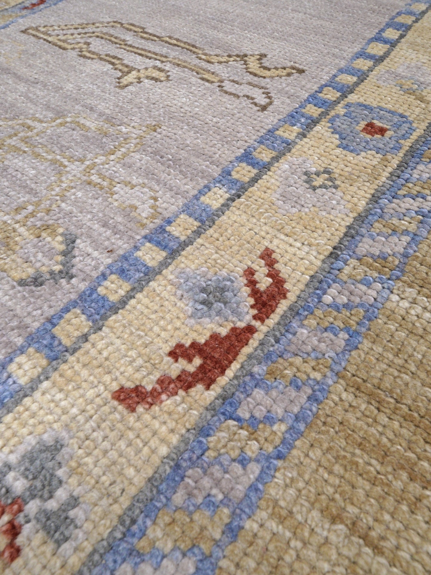 Light olive Turkish Oushak rug with warm ivory border, powder blue floral motifs, soft gray, taupe, and rust accents, hand-knotted wool 10x14 area rug from Indigo Rugs Burlingame Bay Area.