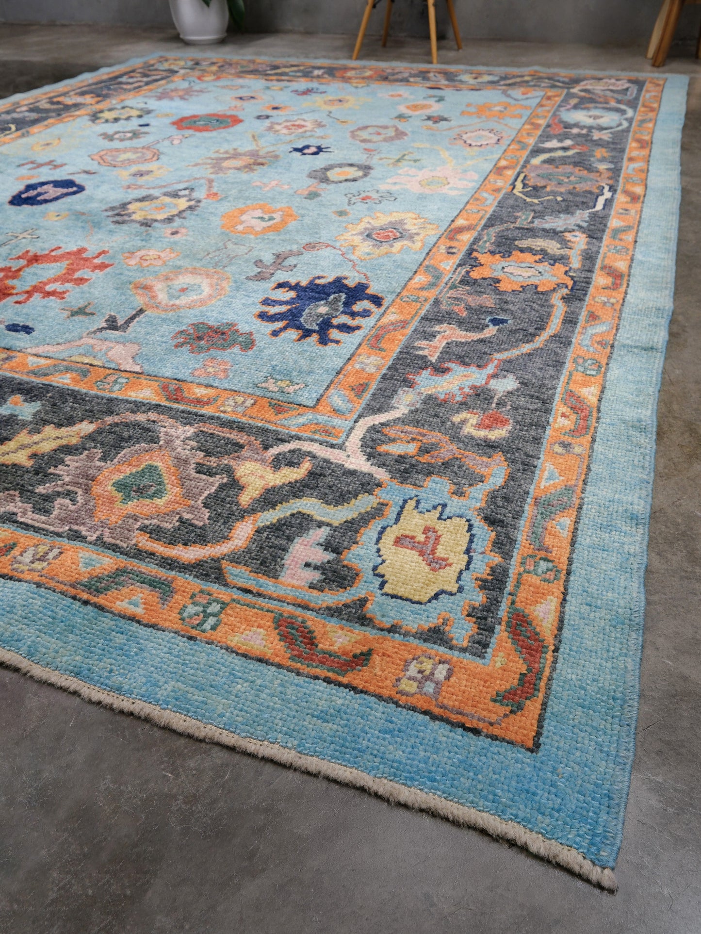 Pale turquoise Turkish Oushak rug with charcoal border, coral orange framing, and colorful abstract floral motifs, hand-knotted wool 8x10 area rug from Indigo Rugs Burlingame Bay Area.