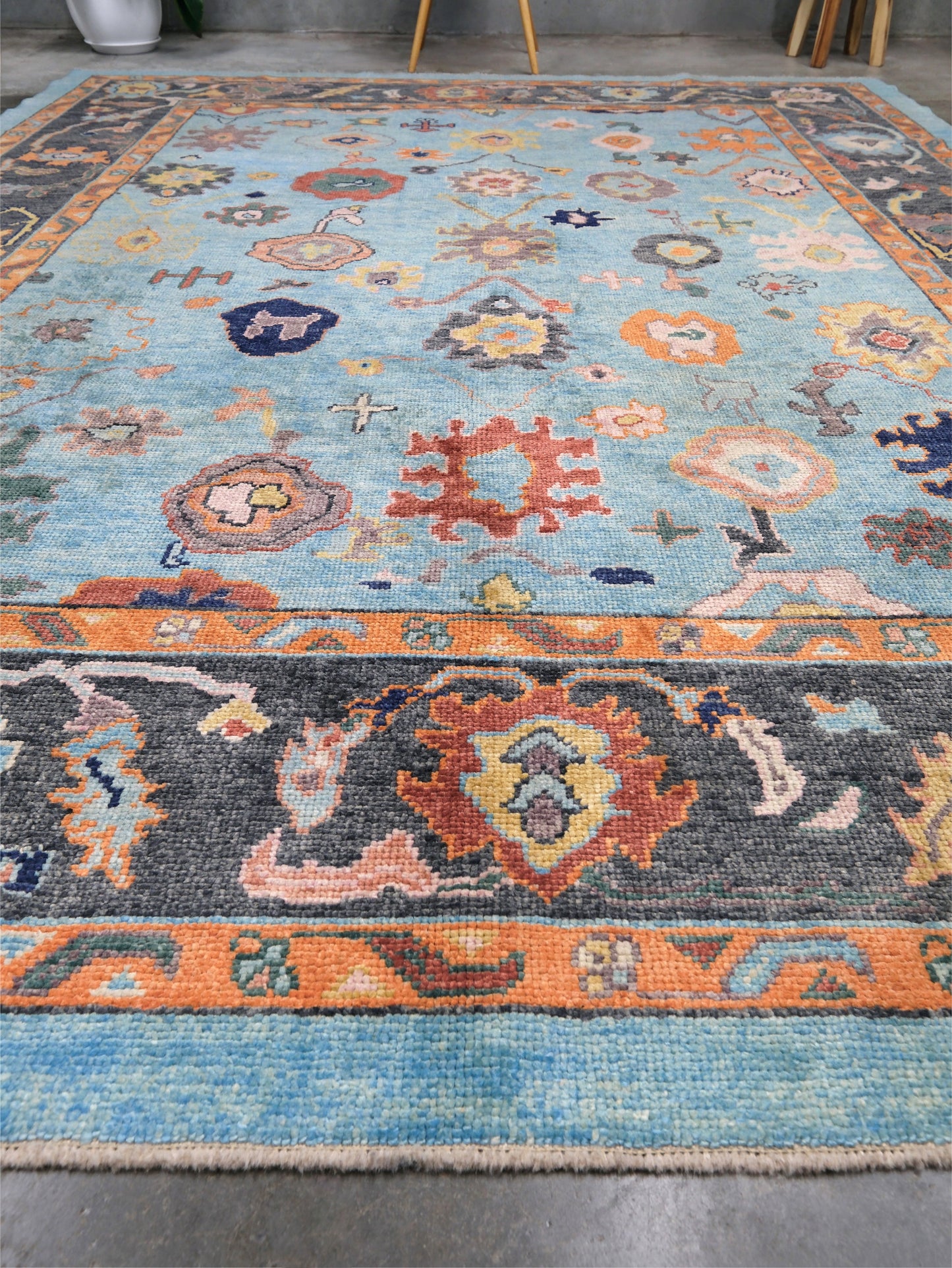 Pale turquoise Turkish Oushak rug with charcoal border, coral orange framing, and colorful abstract floral motifs, hand-knotted wool 8x10 area rug from Indigo Rugs Burlingame Bay Area.