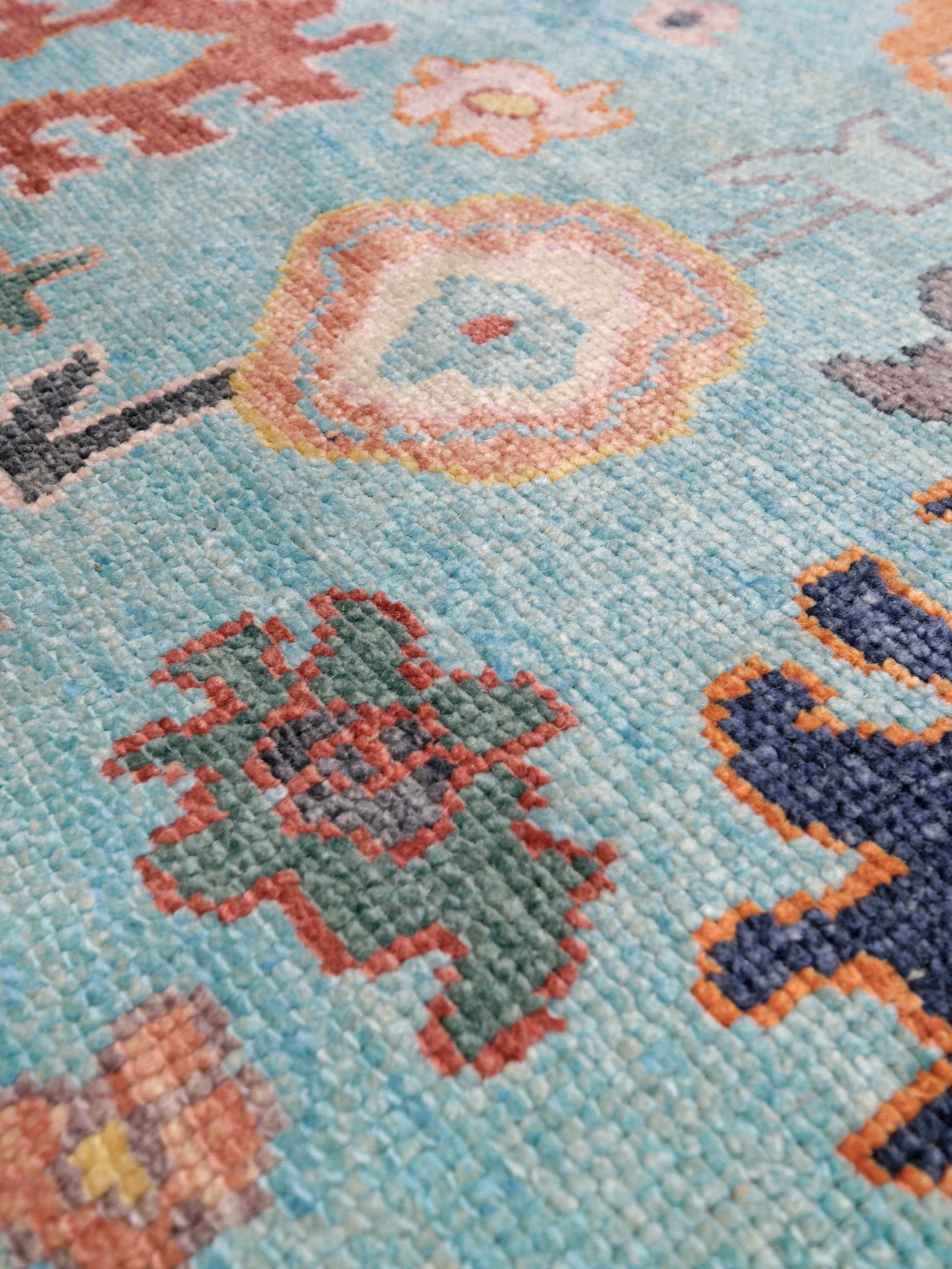 Pale turquoise Turkish Oushak rug with charcoal border, coral orange framing, and colorful abstract floral motifs, hand-knotted wool 8x10 area rug from Indigo Rugs Burlingame Bay Area.