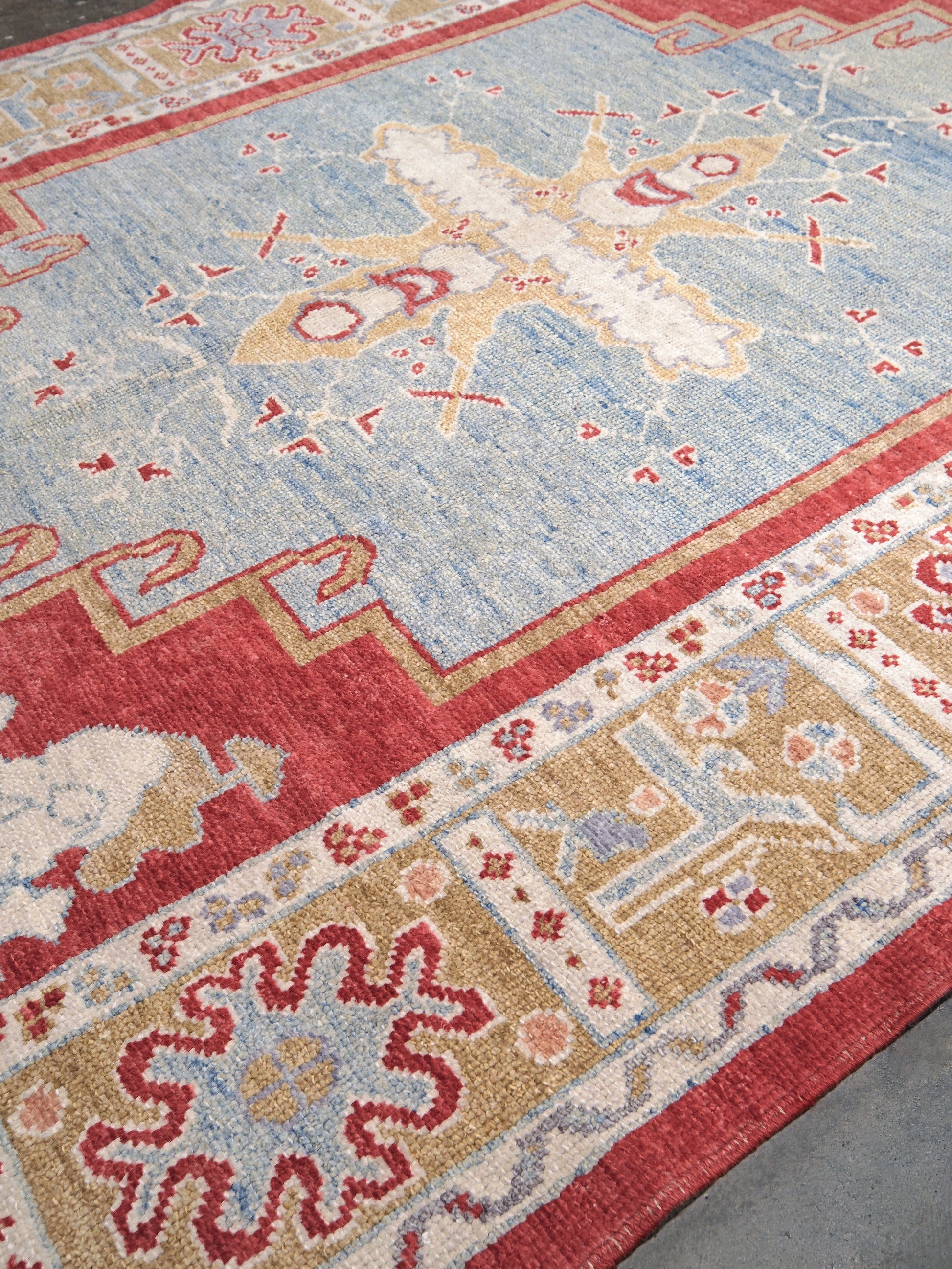 Vibrant soft sky blue and coral 7x10 Turkish Oushak rug with central medallion, golden beige border, floral motifs and warm ivory accents, handmade wool from Indigo Rugs Burlingame Bay Area.