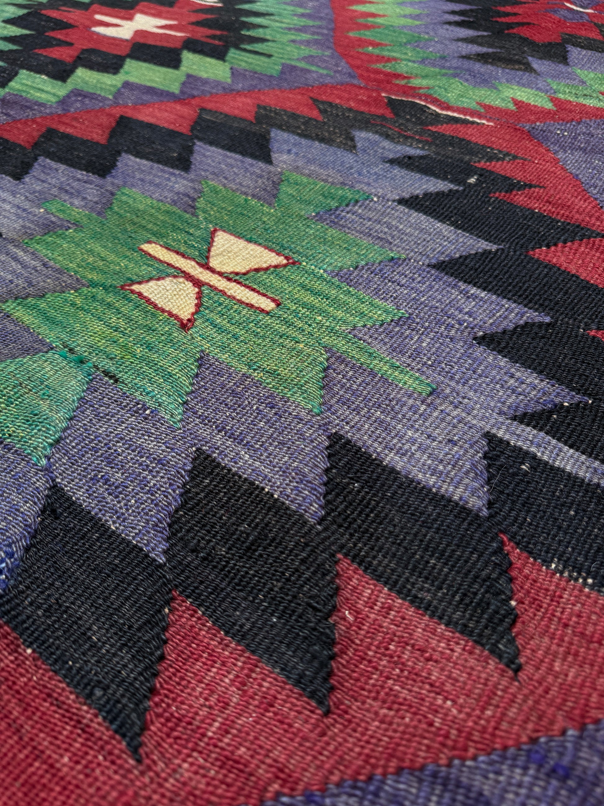Close-up of a colorful patterned fabric with geometric design. Vintage Esme Turkish tribal kilim rug featuring geometric design in raspberry red, blue violet, emerald green, handmade 6x10 perfect for boho style 