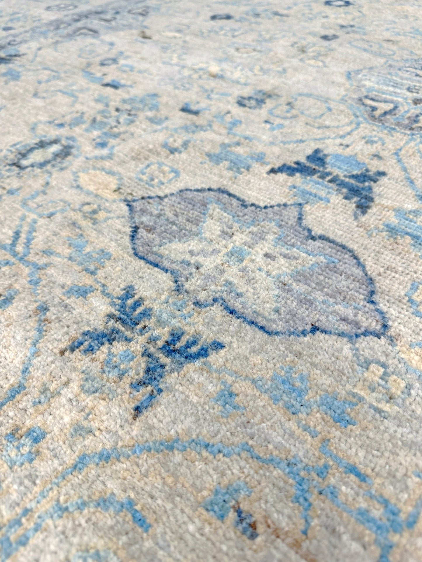 close up of Neutral transitional handmade 8x10 rug with muted gray, ivory, and layered blue tones. Soft Sultanabad-inspired floral motifs, perfect for living rooms, dining spaces, or bedrooms. Contemporary yet timeless, from a rug shop in Burlingame, San Francisco Bay Area, CA with free shipping.
