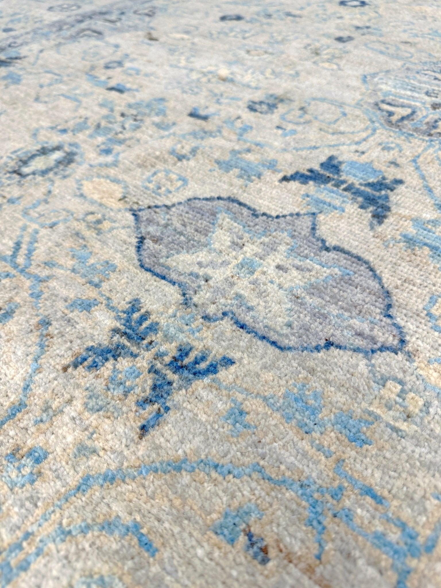 close up of Neutral transitional handmade 8x10 rug with muted gray, ivory, and layered blue tones. Soft Sultanabad-inspired floral motifs, perfect for living rooms, dining spaces, or bedrooms. Contemporary yet timeless, from a rug shop in Burlingame, San Francisco Bay Area, CA with free shipping.