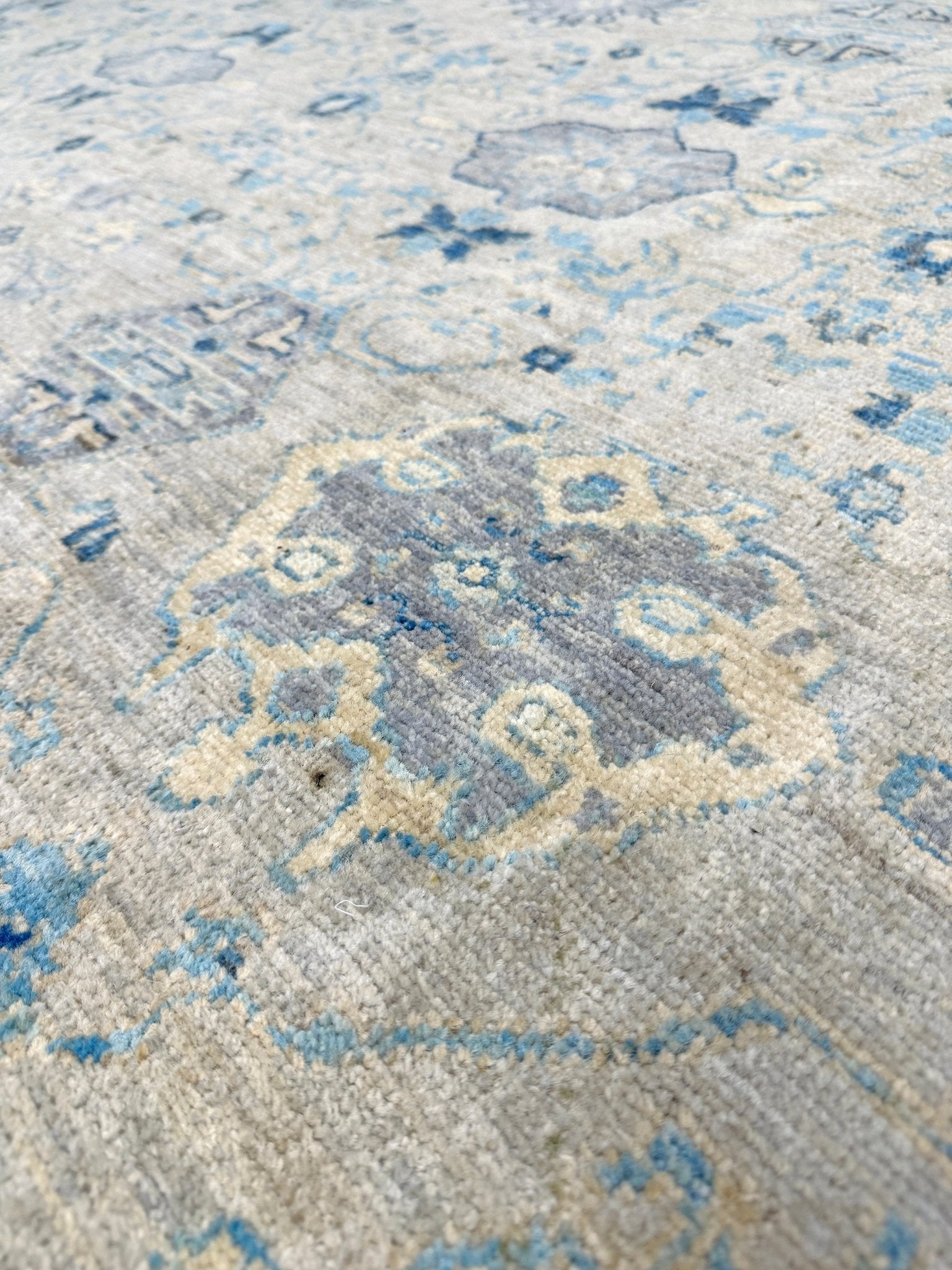 close up of Neutral transitional handmade 8x10 decorative rug with muted gray, ivory, and layered blue tones. Soft Sultanabad-inspired floral motifs, perfect for living rooms, dining spaces, or bedrooms. Contemporary yet timeless, from a rug shop in Burlingame, San Francisco Bay Area, CA with free shipping.