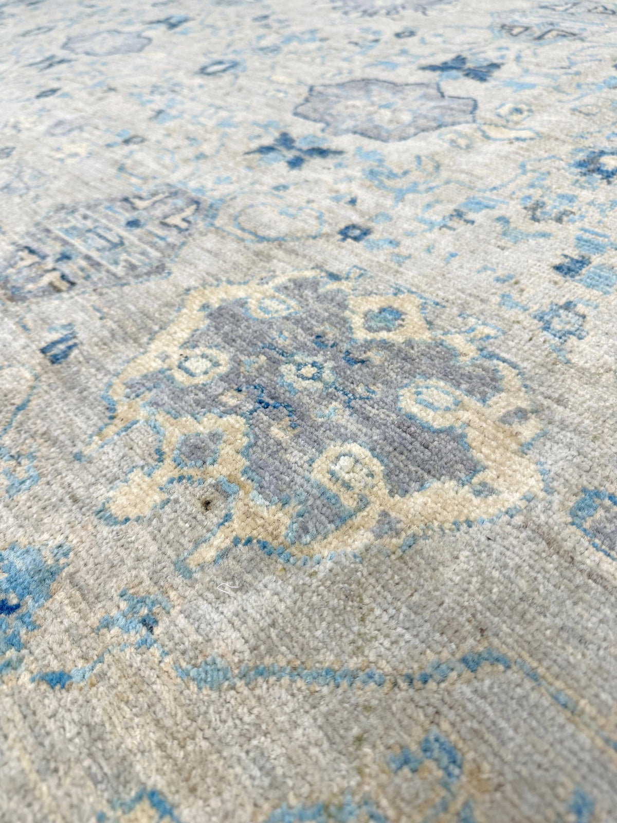 Neutral blue Oushak Turkish rug with ivory and pale blue-gray field, soft floral motifs, muted border, beige and deeper blue accents, handmade wool 8x10 from Indigo Rugs Burlingame Bay Area.