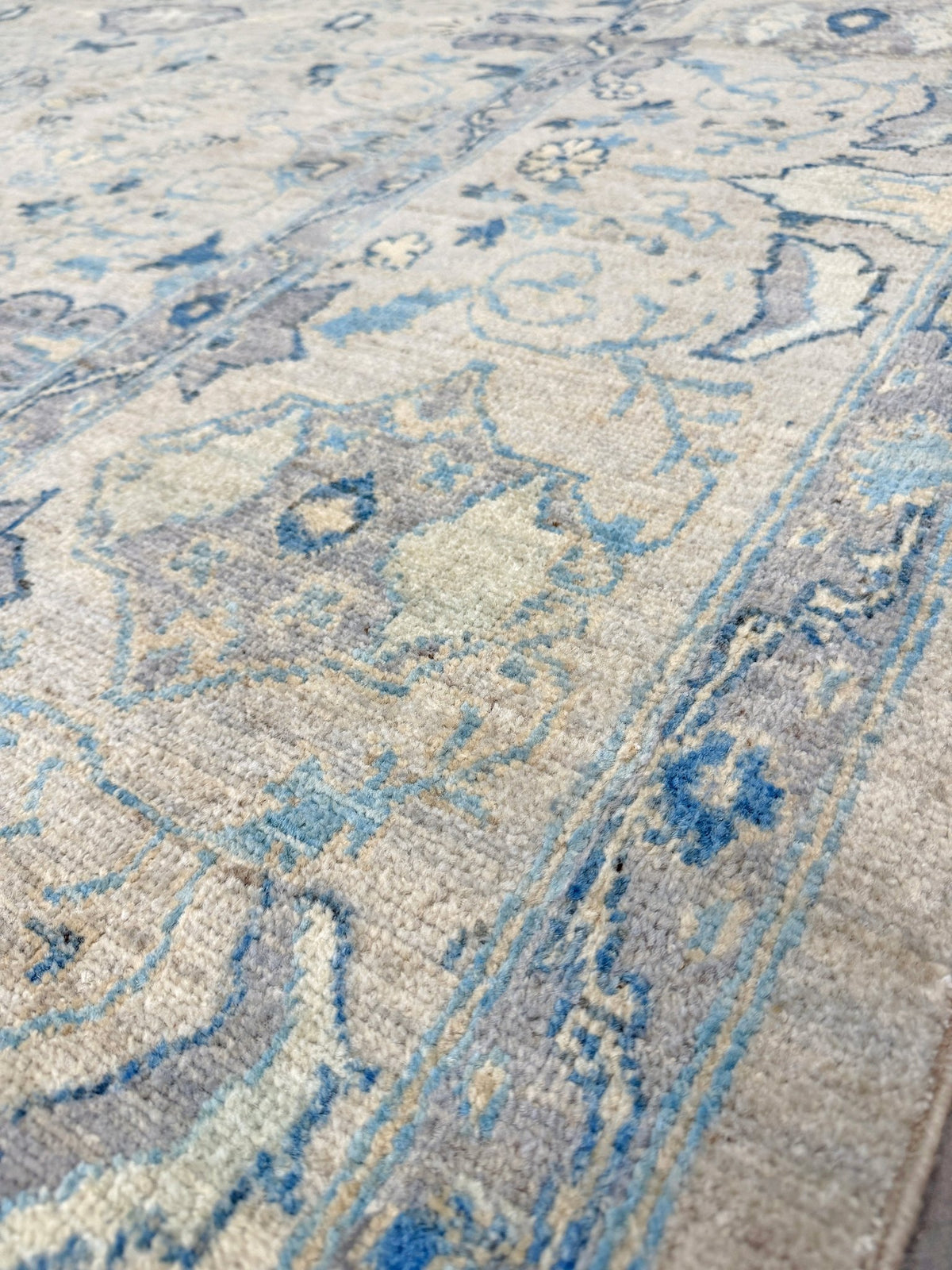 Neutral blue Oushak Turkish rug with ivory and pale blue-gray field, soft floral motifs, muted border, beige and deeper blue accents, handmade wool 8x10 from Indigo Rugs Burlingame Bay Area.