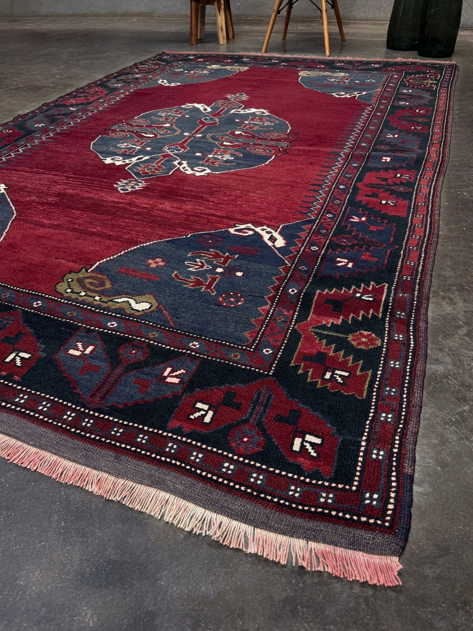 Decorative rug with intricate patterns on a gray floor. Antique kiz bergama turkish rug 6x8 deep madder red field indigo clue medallion anatolian village rug 1920s indigo rugs san francisco bay area