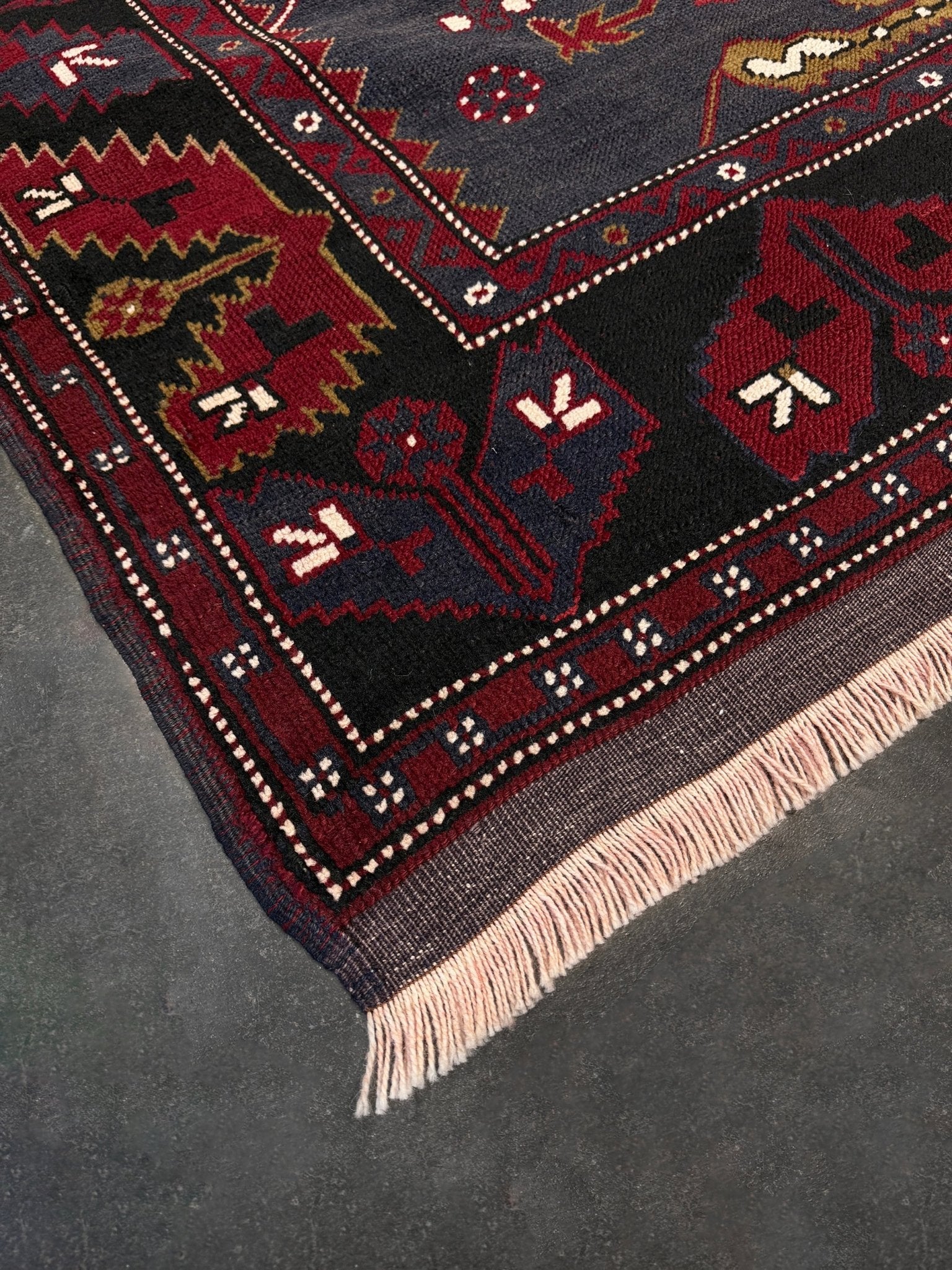 Close-up of a patterned rug with geometric designs on a dark surface. Antique kiz bergama turkish rug 6x8 deep madder red field indigo clue medallion anatolian village rug 1920s indigo rugs san francisco bay area