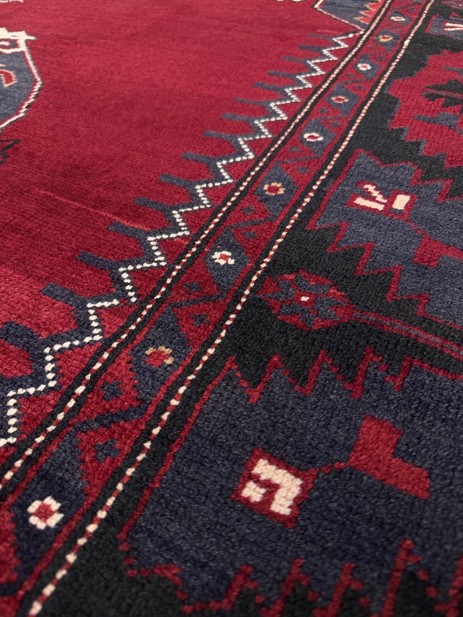 Close-up of a red and black patterned rug. Antique kiz bergama turkish rug 6x8 deep madder red field indigo clue medallion anatolian village rug 1920s indigo rugs san francisco bay area