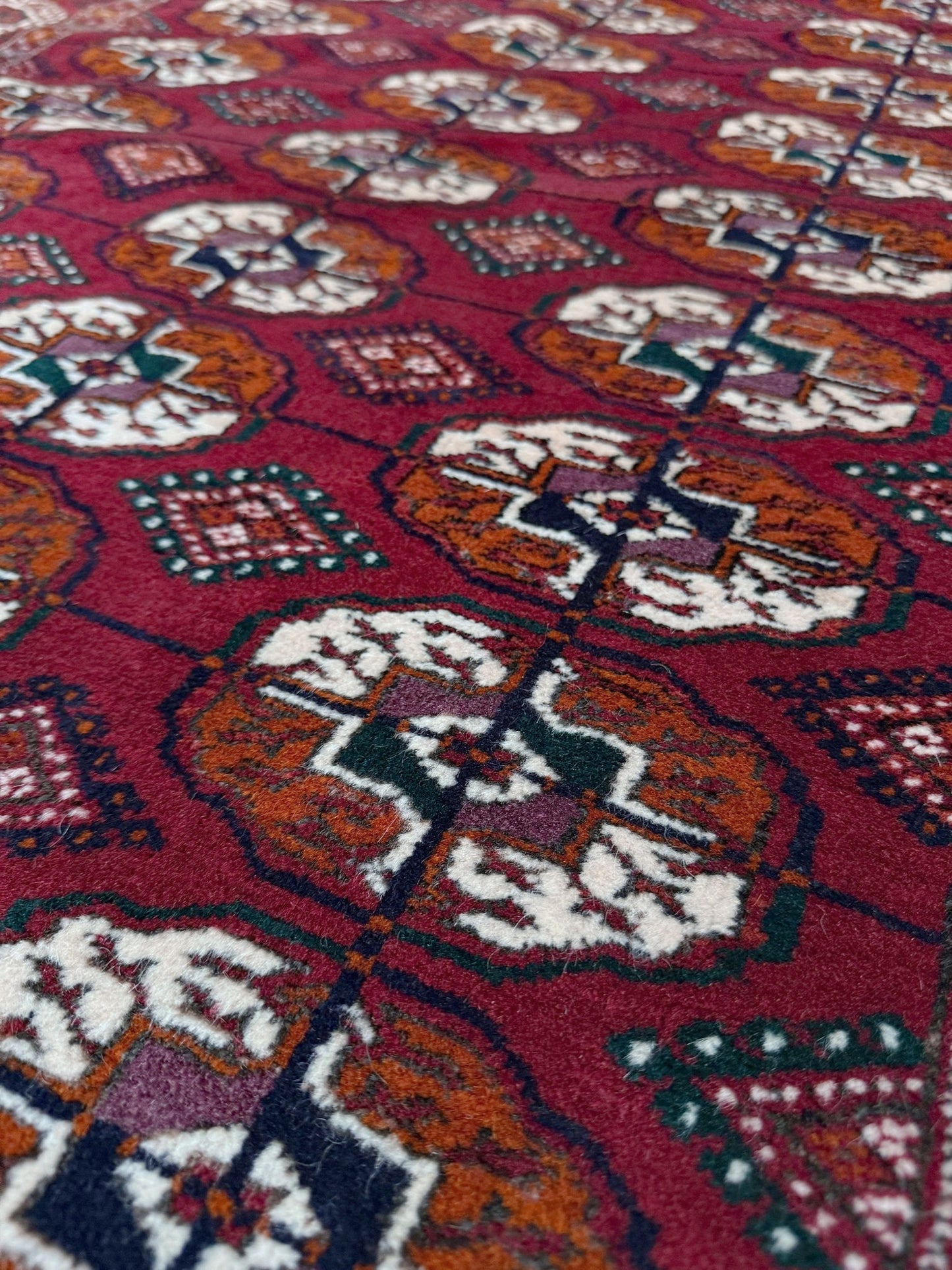 Vintage Turkmen Burgundy Bukhara rug 4x6 with repeating ivory gul motifs, velvety wool pile and classic tribal border. Hand-knotted wool decorative scatter rug for living room bedroom office from Indigo Rugs, Burlingame — the best rug shop in the San Francisco Bay Area. Free shipping.