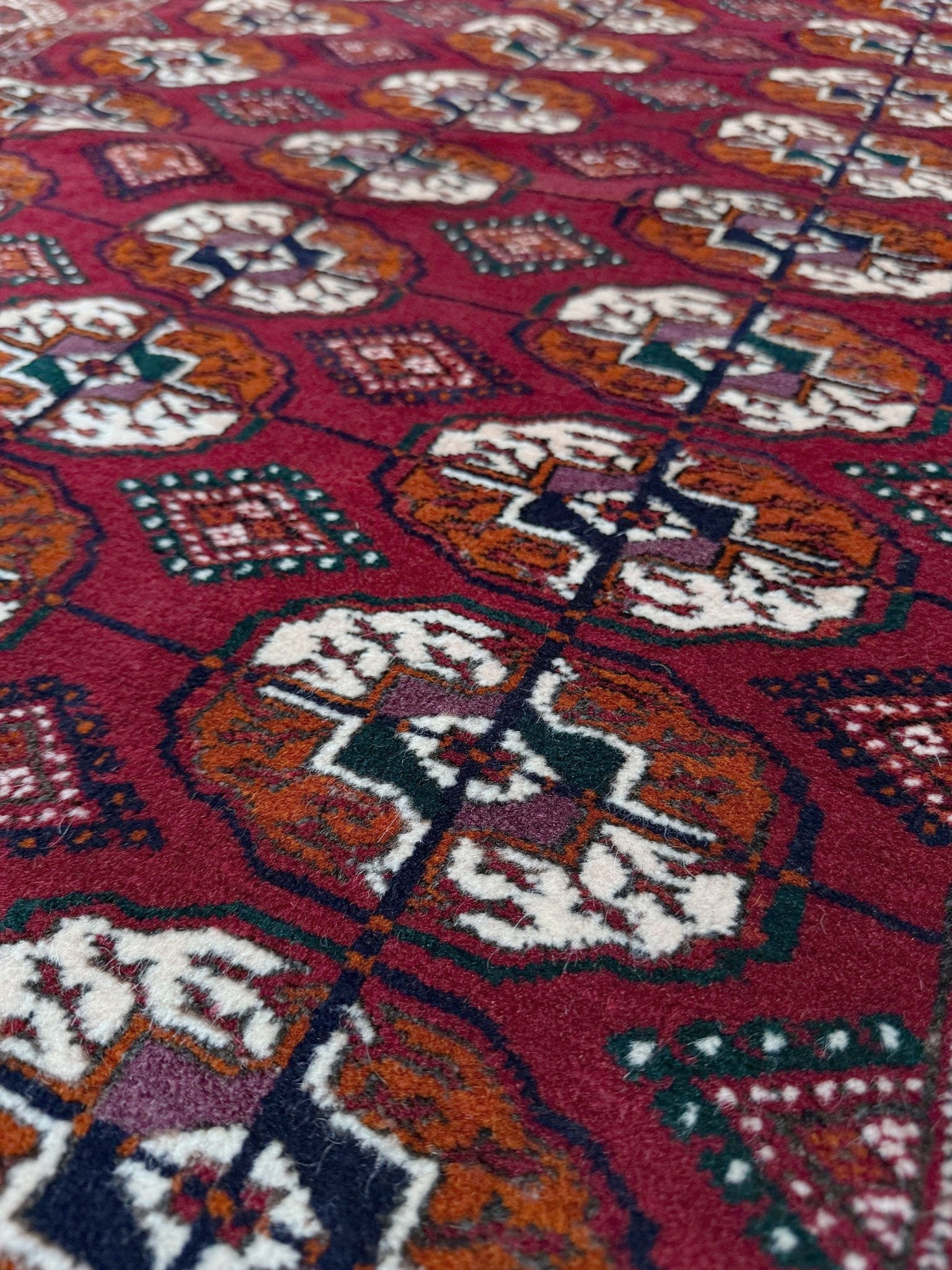 Vintage Turkmen Burgundy Bukhara rug 4x6 with repeating ivory gul motifs, velvety wool pile and classic tribal border. Hand-knotted wool decorative scatter rug for living room bedroom office from Indigo Rugs, Burlingame — the best rug shop in the San Francisco Bay Area. Free shipping.