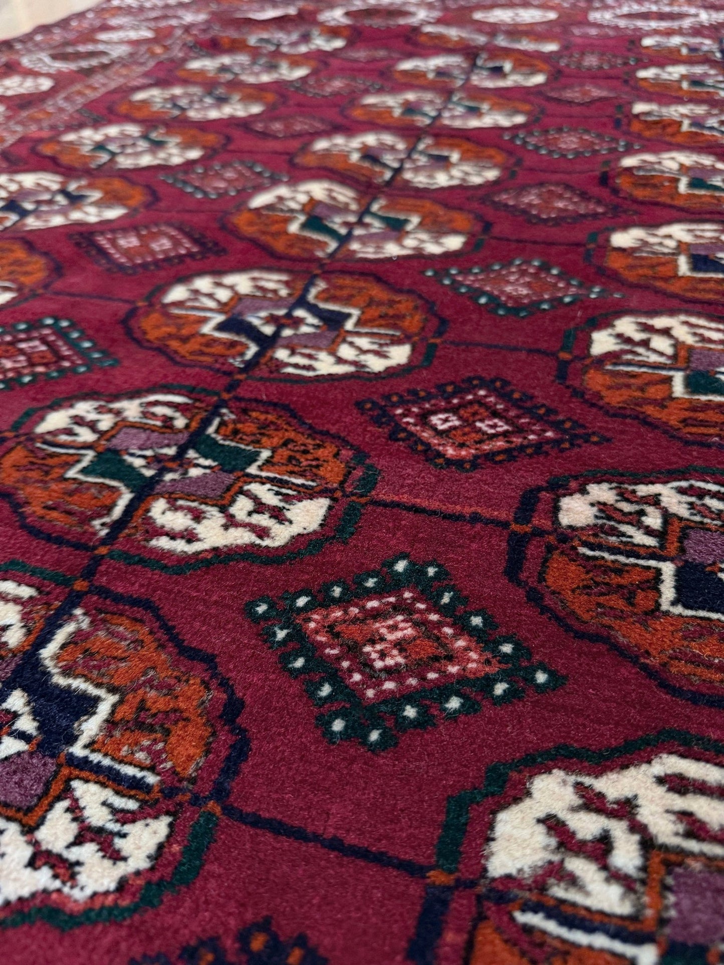 Vintage Turkmen Burgundy Bukhara rug 4x6 with repeating ivory gul motifs, velvety wool pile and classic tribal border. Hand-knotted wool scatter rug for living room bedroom office from Indigo Rugs, Burlingame — the best rug shop in the San Francisco Bay Area. Free shipping.