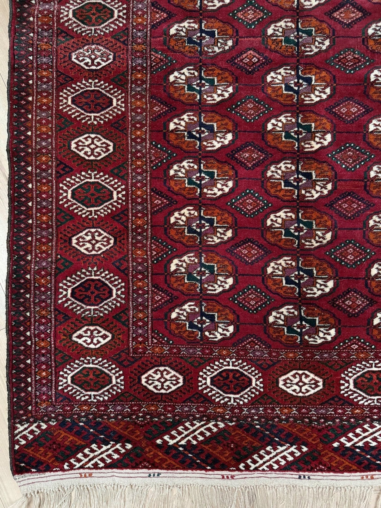 Vintage Turkmen Burgundy Bukhara rug 4x6 with repeating ivory gul motifs, velvety wool pile and classic tribal border. Hand-knotted wool decorative scatter rug for living room bedroom office from Indigo Rugs, Burlingame — the best rug shop in the San Francisco Bay Area. Free shipping.