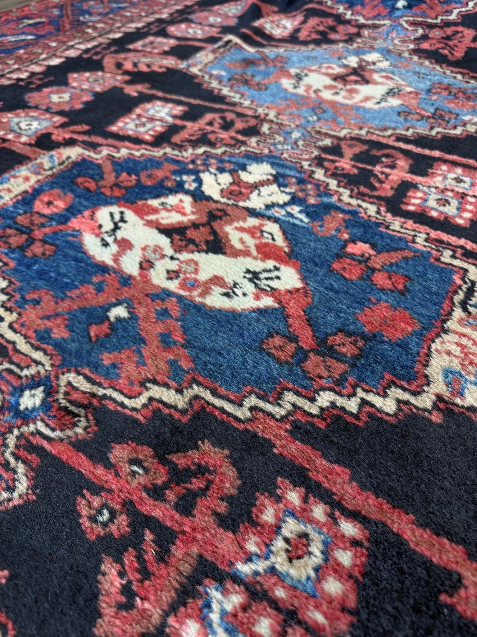 Close-up of an intricately designed rug with floral patterns. vintage Komurcu Kula Turkish rug with black brown field, madder red borders, handmade wool area rug 6x10 from Indigo Rugs Burlingame Bay Area.