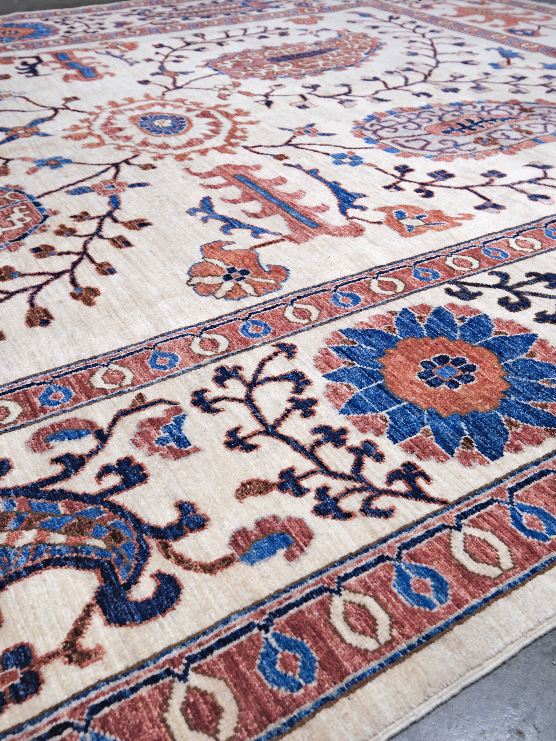Ivory Suzani style handmade Turkish wool rug with paisley motifs, branching vines, flowers, indigo blue and rust accents, 9x12 from Indigo Rugs Burlingame Bay Area.