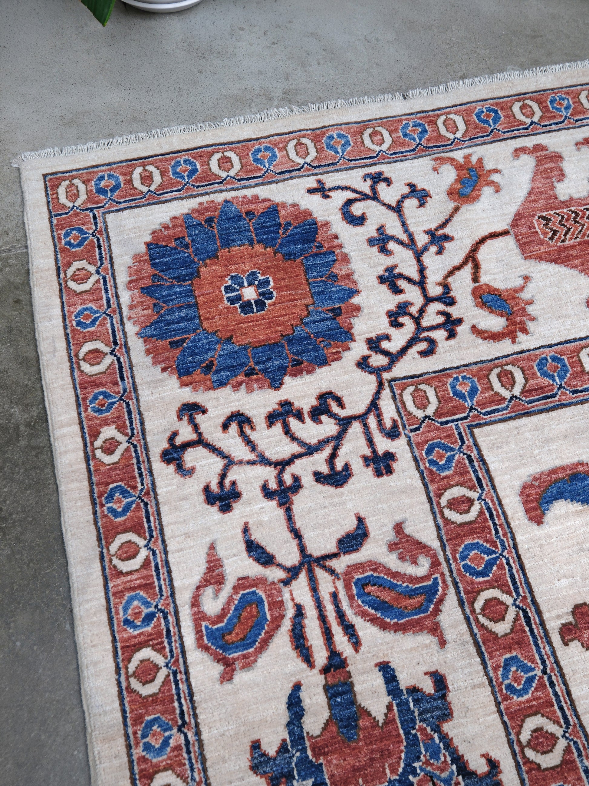 Ivory Suzani style handmade Turkish wool rug with paisley motifs, branching vines, flowers, indigo blue and rust accents, 9x12 from Indigo Rugs Burlingame Bay Area.