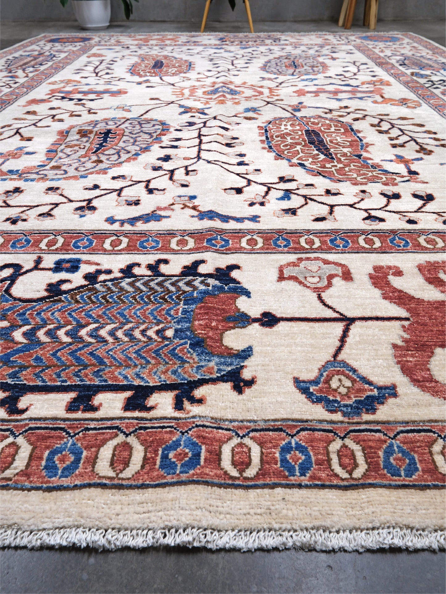Ivory Suzani style handmade Turkish wool rug with paisley motifs, branching vines, flowers, indigo blue and rust accents, 9x12 from Indigo Rugs Burlingame Bay Area.