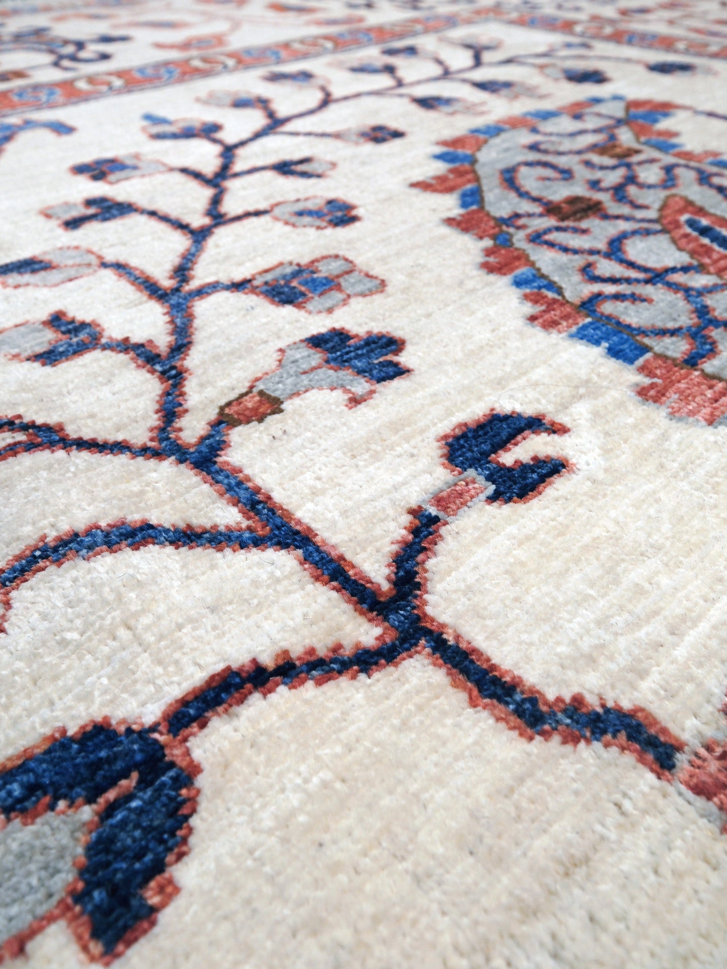 Ivory Suzani style handmade Turkish wool rug with paisley motifs, branching vines, flowers, indigo blue and rust accents, 9x12 from Indigo Rugs Burlingame Bay Area.