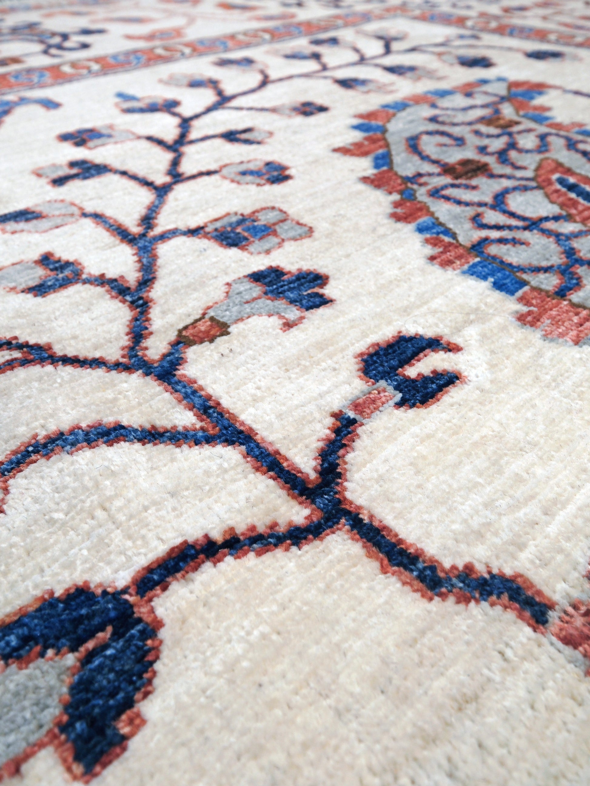 Ivory Suzani style handmade Turkish wool rug with paisley motifs, branching vines, flowers, indigo blue and rust accents, 9x12 from Indigo Rugs Burlingame Bay Area.