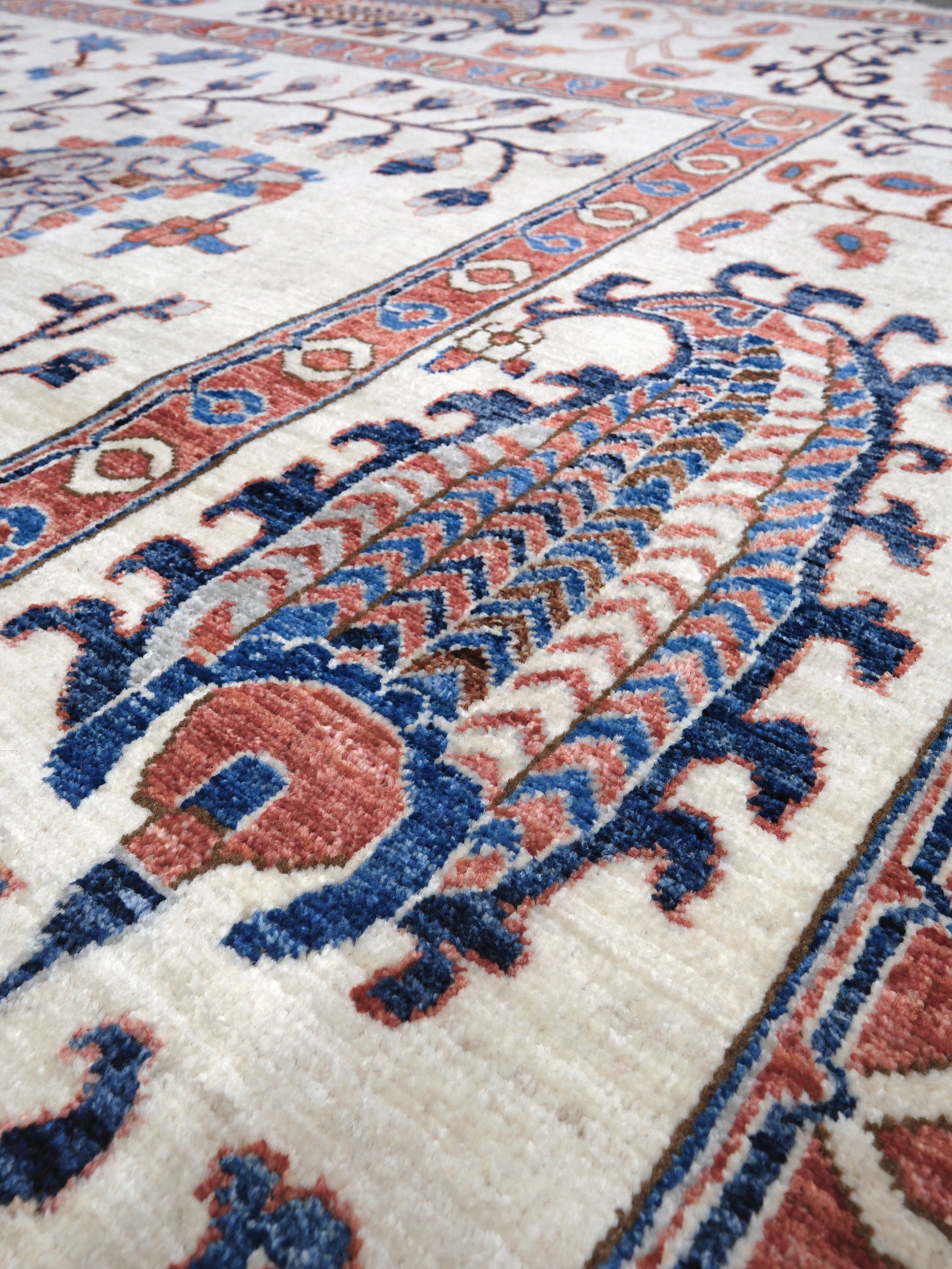 Ivory Suzani style handmade Turkish wool rug with paisley motifs, branching vines, flowers, indigo blue and rust accents, 9x12 from Indigo Rugs Burlingame Bay Area.