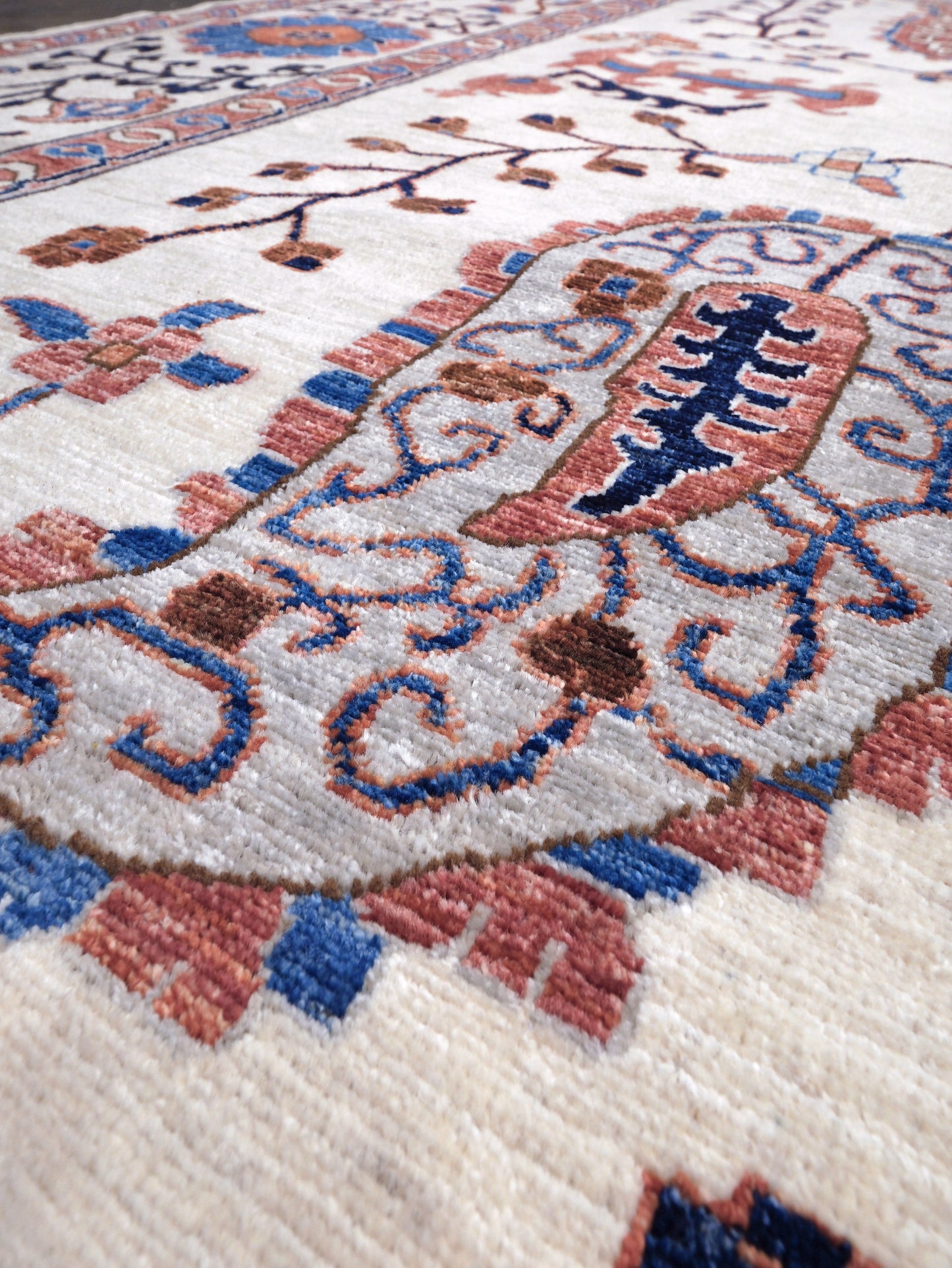 Ivory Suzani style handmade Turkish wool rug with paisley motifs, branching vines, flowers, indigo blue and rust accents, 9x12 from Indigo Rugs Burlingame Bay Area.