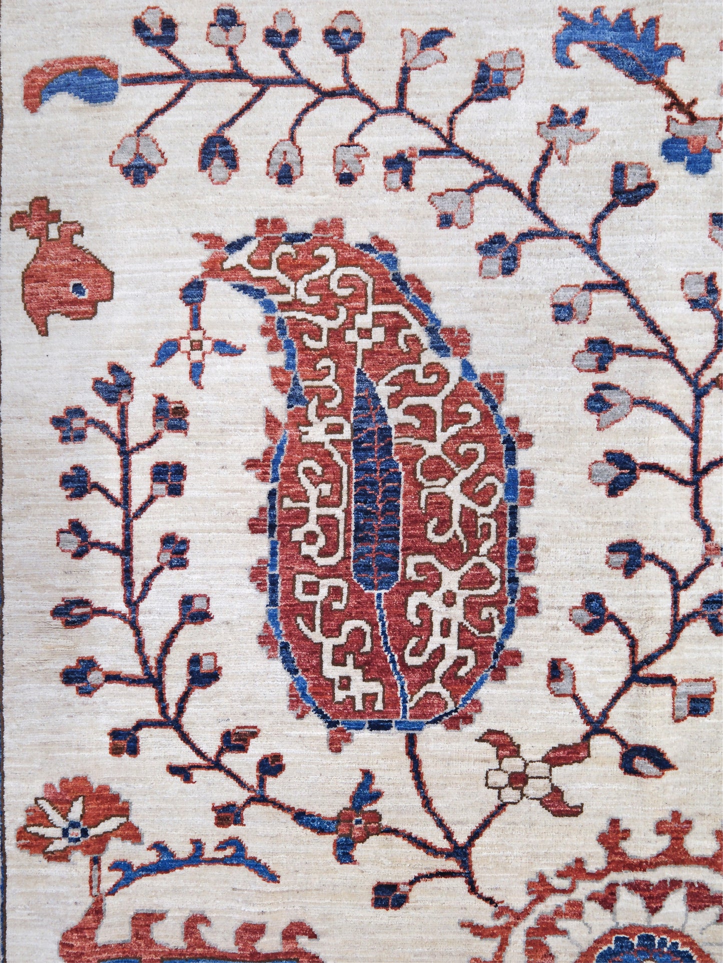 Ivory Suzani style handmade Turkish wool rug with paisley motifs, branching vines, flowers, indigo blue and rust accents, 9x12 from Indigo Rugs Burlingame Bay Area.
