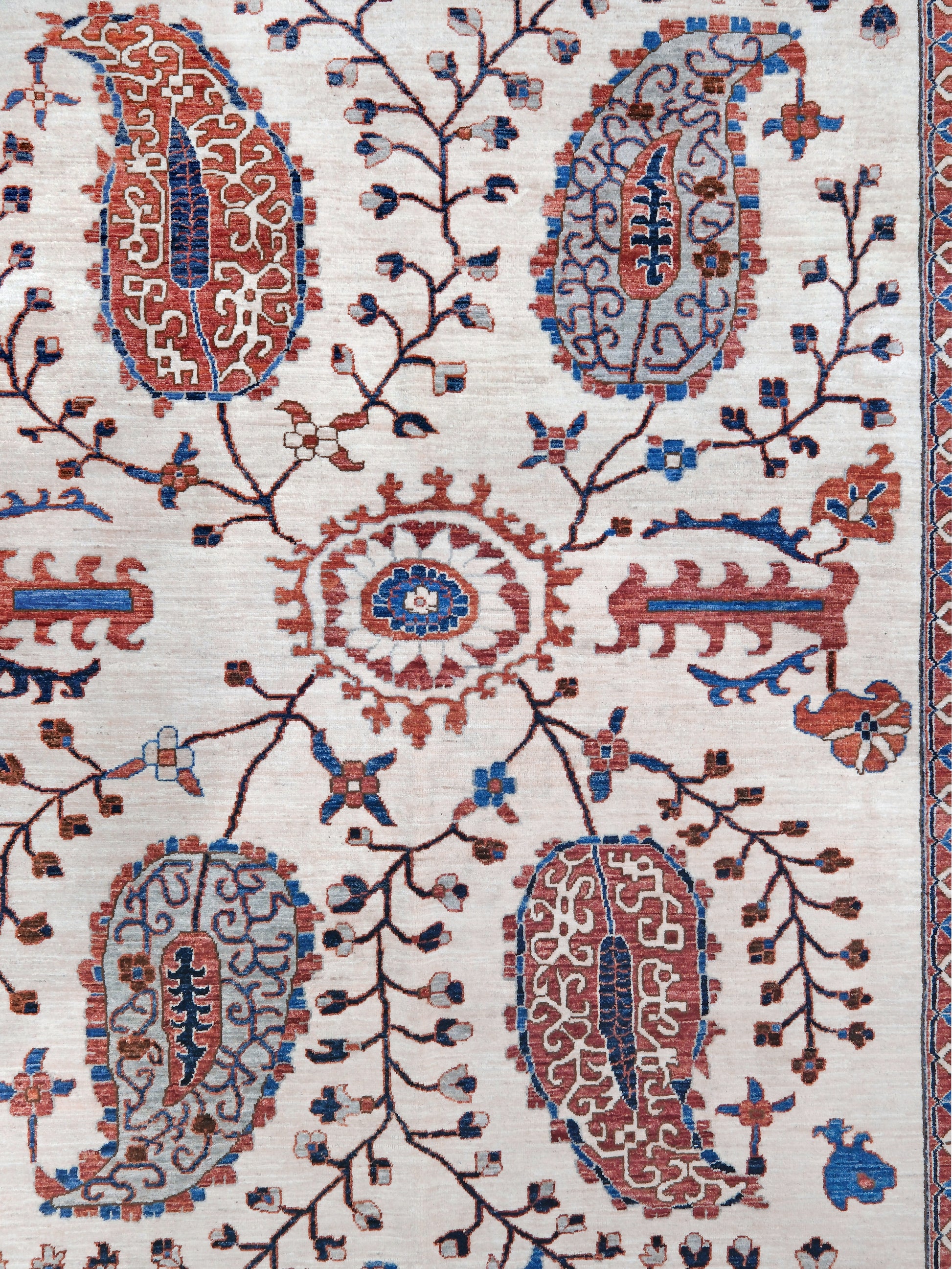 Ivory Suzani style handmade Turkish wool rug with paisley motifs, branching vines, flowers, indigo blue and rust accents, 9x12 from Indigo Rugs Burlingame Bay Area.