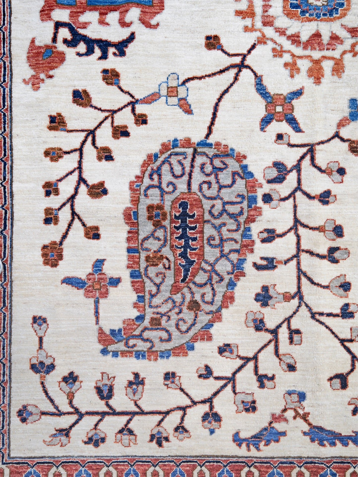 Ivory Suzani style handmade Turkish wool rug with paisley motifs, branching vines, flowers, indigo blue and rust accents, 9x12 from Indigo Rugs Burlingame Bay Area.