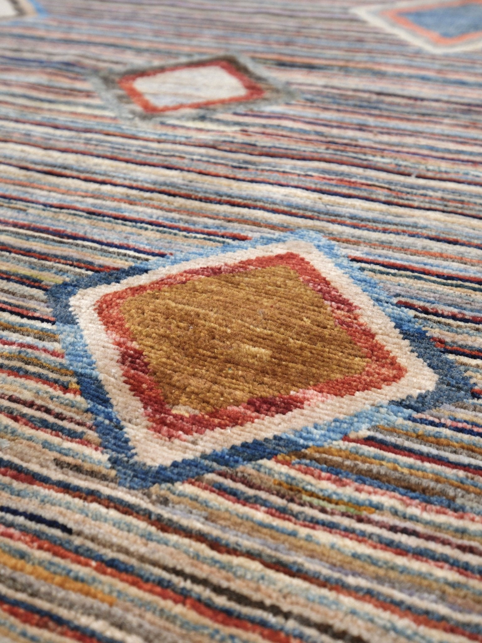 Modern Turkish Gabbeh style handmade wool rug with colorful diamond medallions on a striped field in blue, red, ivory, gray, green, camel and lavender, 7x10 from Indigo Rugs Burlingame Bay Area.