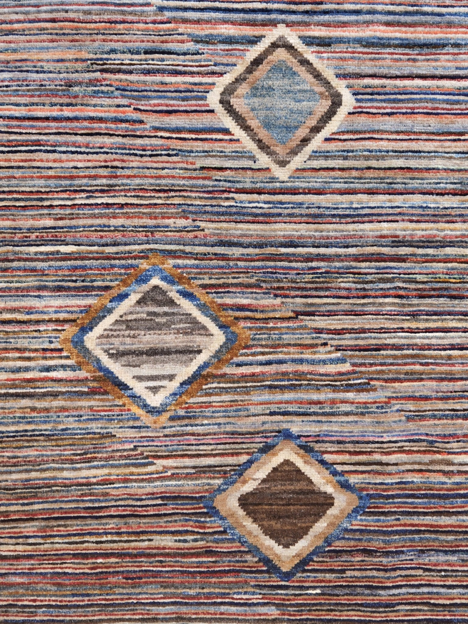 Modern Turkish Gabbeh style handmade wool rug with colorful diamond medallions on a striped field in blue, red, ivory, gray, green, camel and lavender, 7x10 from Indigo Rugs Burlingame Bay Area.