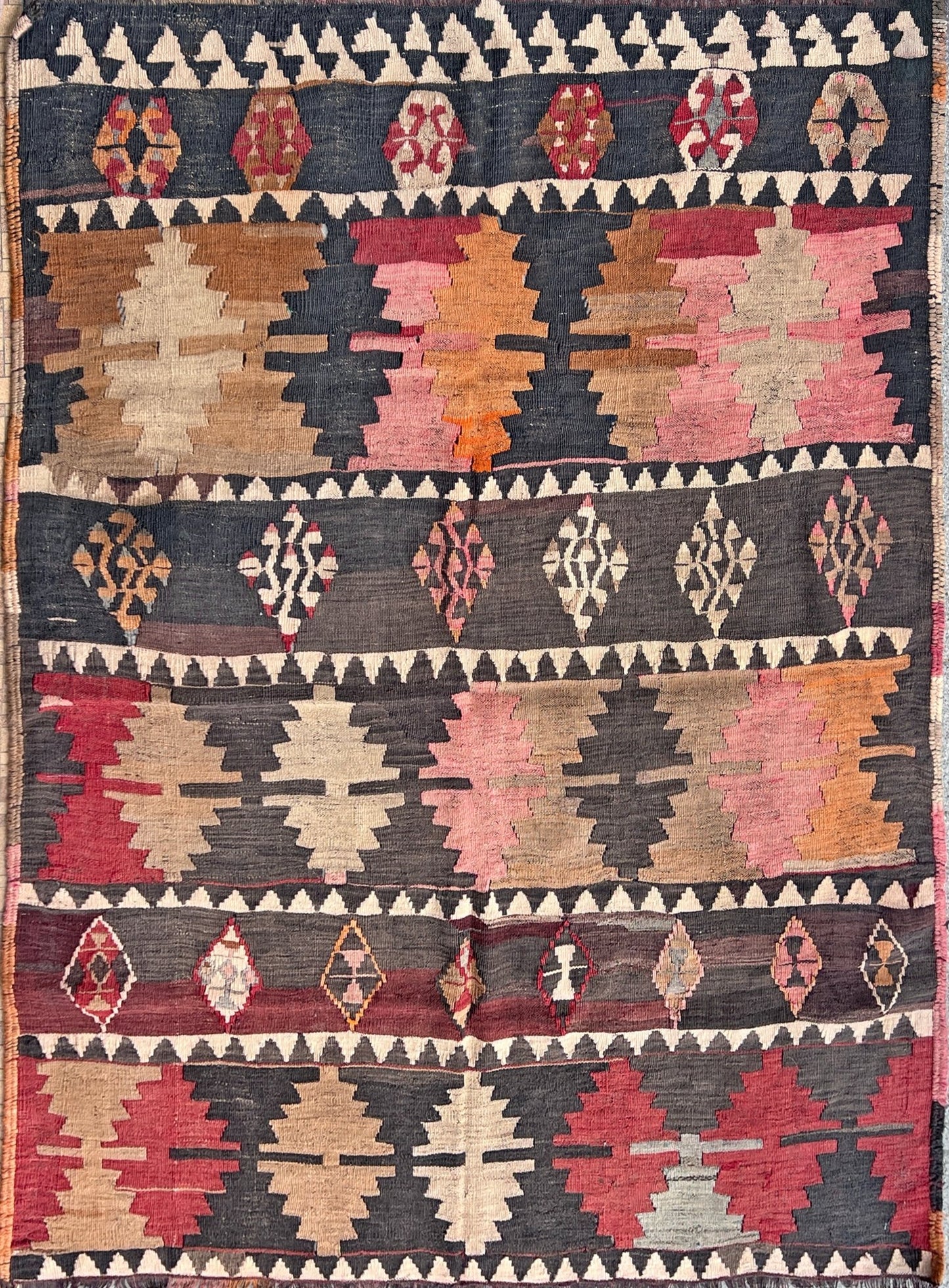 5x7 Kurdish Kilim rug from Eastern Turkey in slitweave technique, featuring bold geometric patterns in red, pink, and earthy tones. Offered by the best Kilim rug store in the San Francisco Bay Area, with free shipping to the US and Canada. A perfect gift idea for this season.