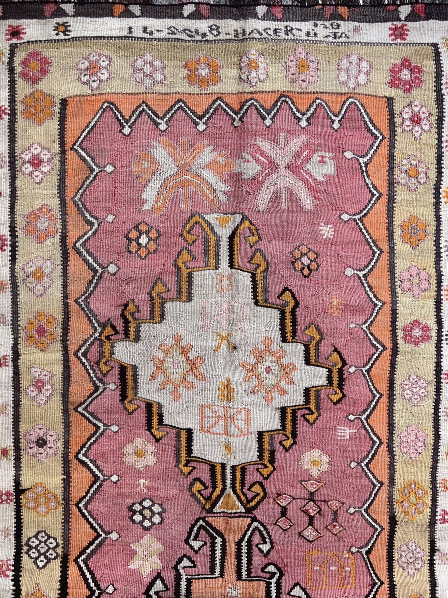 Traditional patterned rug with geometric design and floral elements.  Vintage Kurdish runner rug from Eastern Turkey, 4x10, with dusty rose and peach medallions, floral borders, and woven inscription dated 1948.