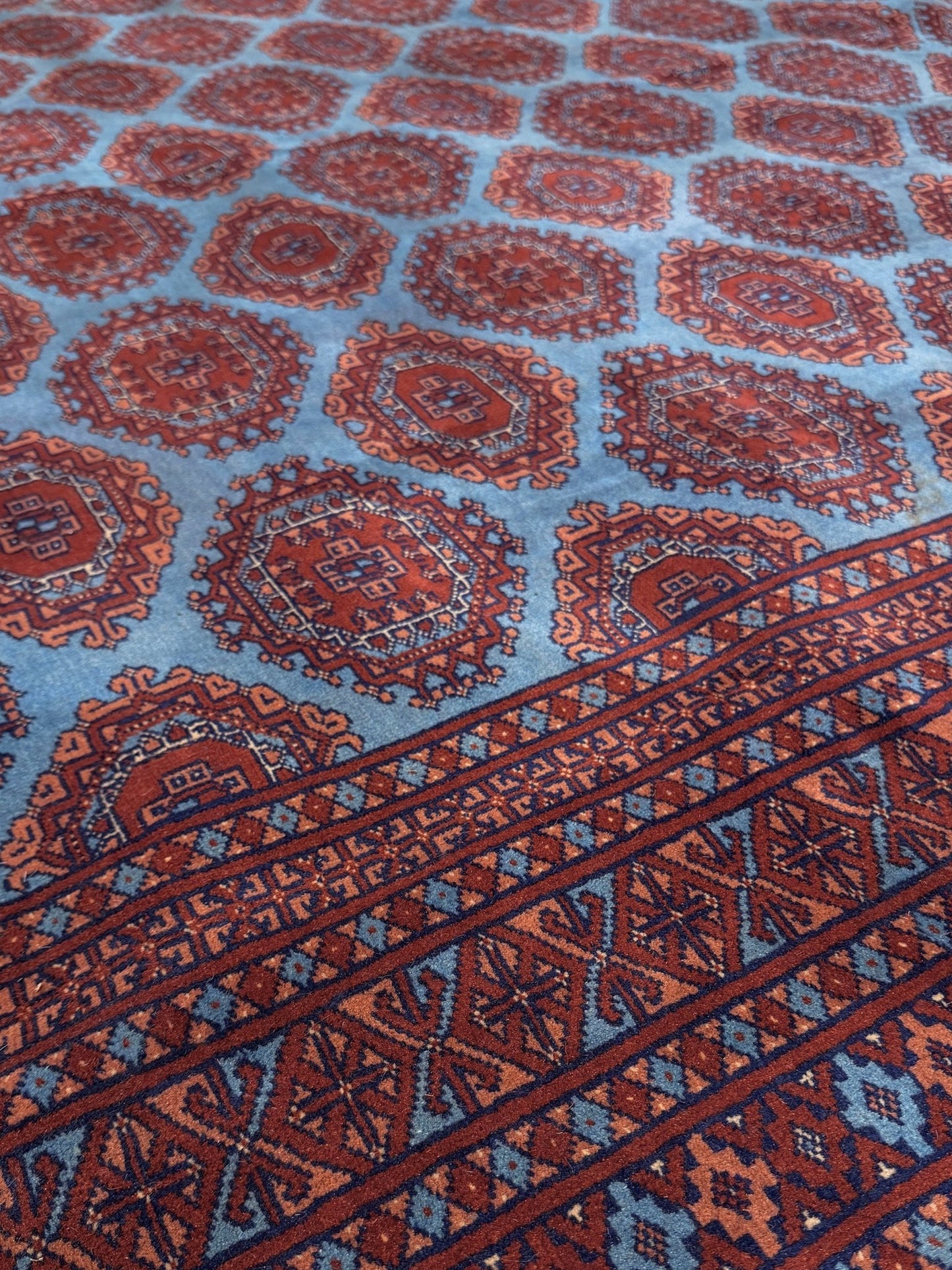 Vintage Uzbek Bukhara rug with sky blue field and repeating brick red gul motifs, navy borders, large handmade merino wool area rug 10x14 with velvety pile from Indigo Rugs Burlingame Bay Area