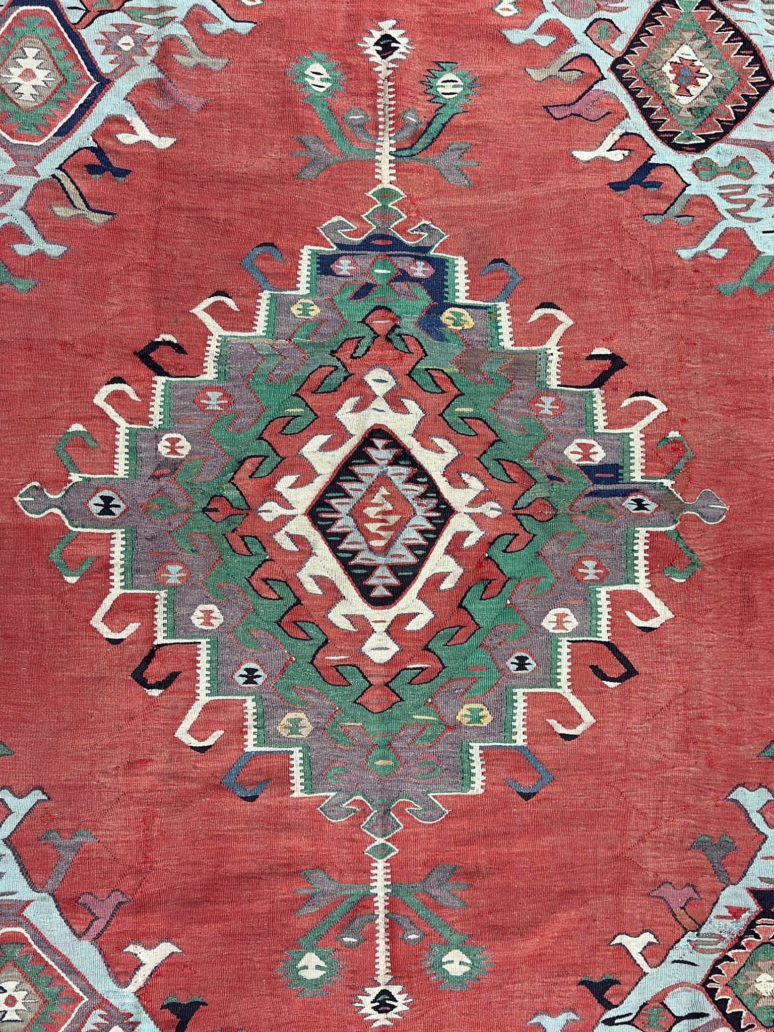 4x10 vintage Turkish Oushak kilim rug with a dusty rose field, geometric tribal medallion, and soft sage, mint, and blue accents — handmade flatweave wool rug from the 1940s, naturally dyed and beautifully aged with mellowed colors and small, well-executed repairs. Perfect for living room or bohemian interior décor — Indigo Rugs.