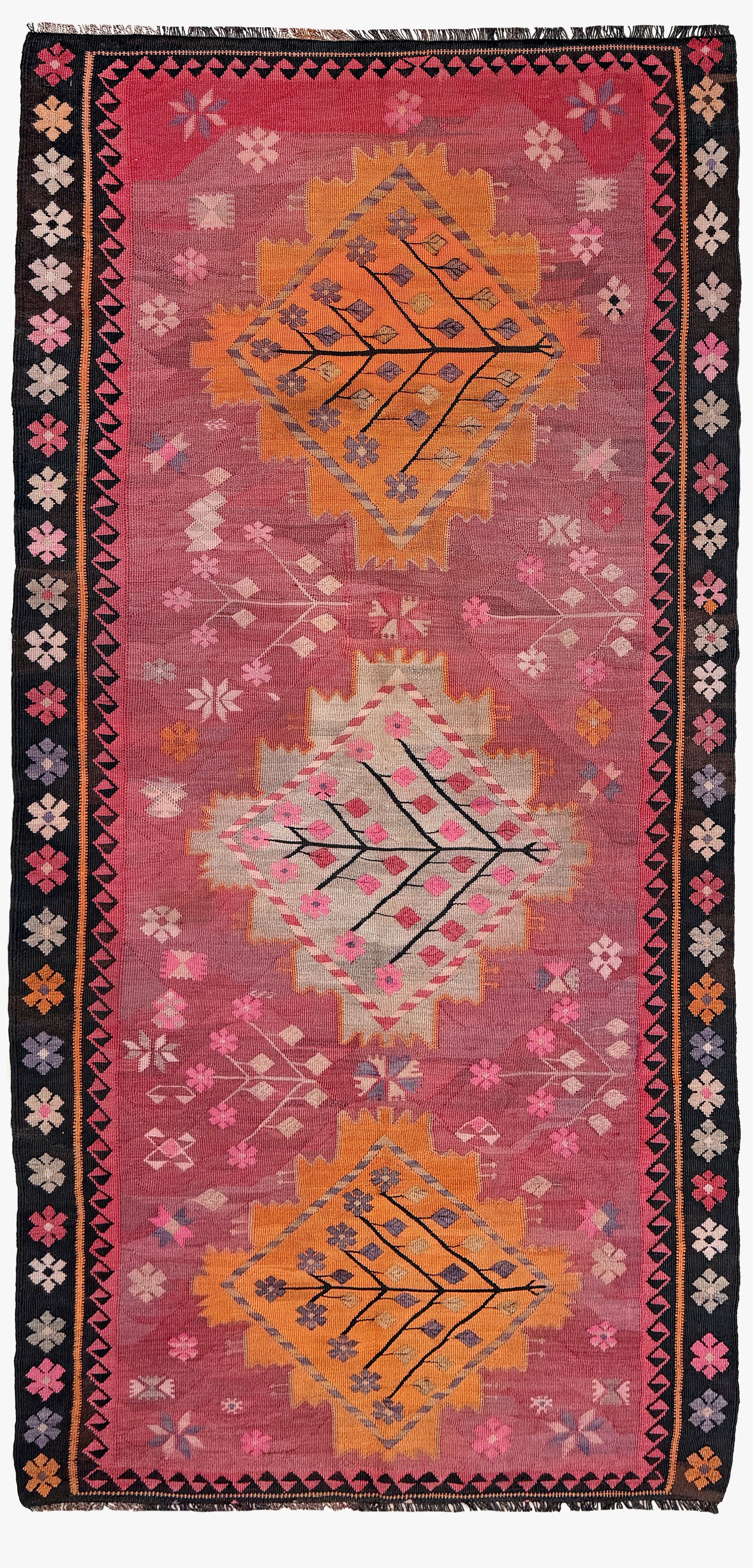 Decorative rug with geometric patterns and floral elements on a pink background. Vintage Kars Turkish kilim rug in dusty pink, warm apricot orange, handwoven from Anatolian wool 5x10. 