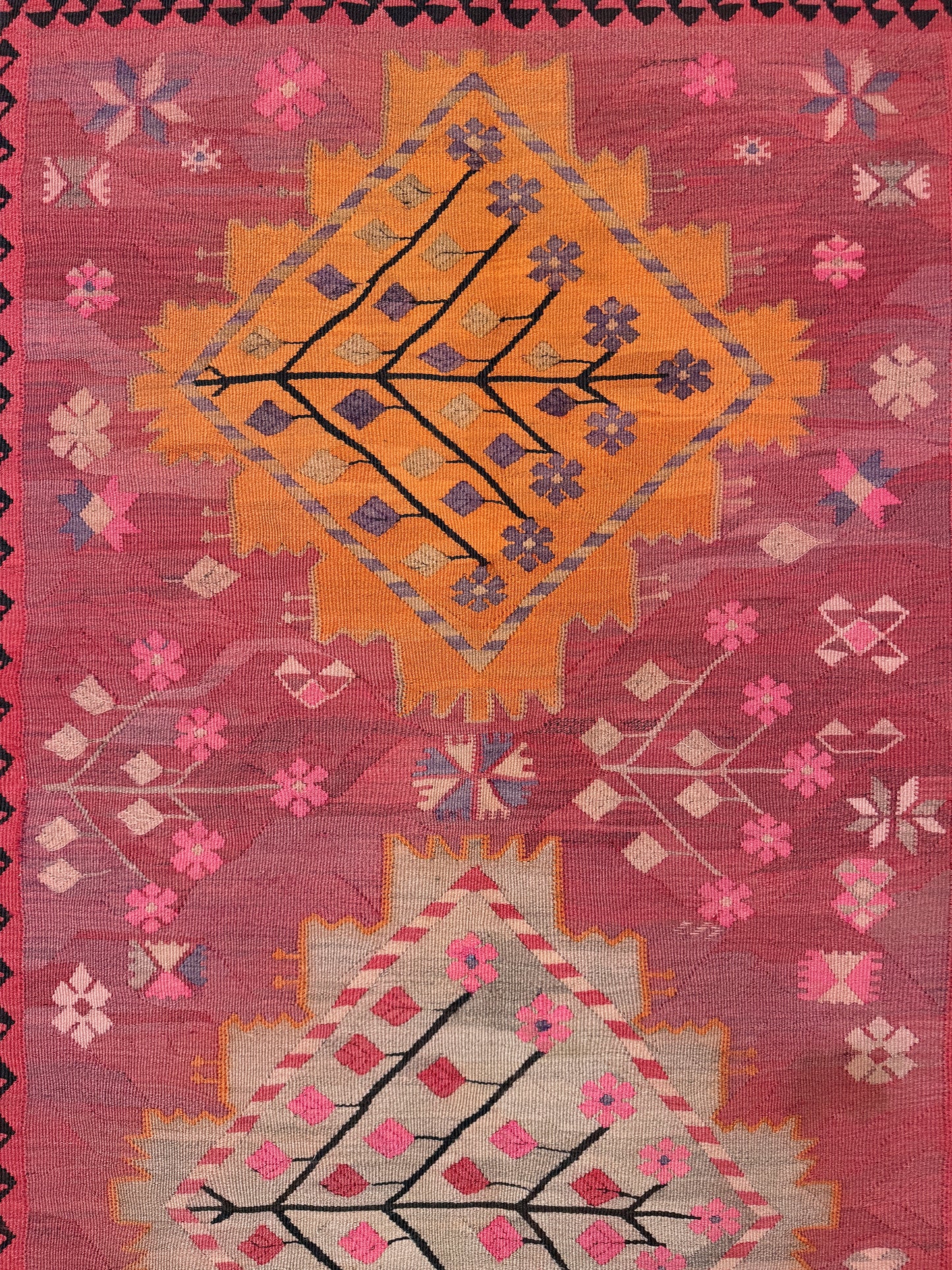Decorative rug with geometric patterns in red, orange, and pink on a red background. Vintage Kars Turkish kilim rug in dusty pink, warm apricot orange, handwoven from Anatolian wool 5x10. 