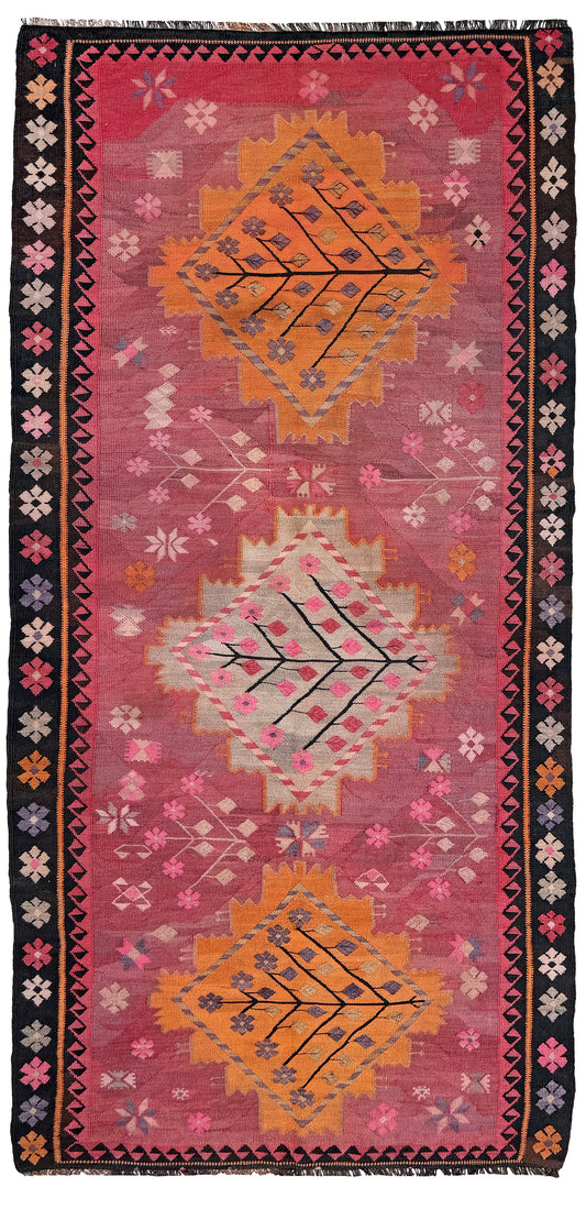 Decorative rug with geometric patterns and floral elements on a pink background. Vintage Kars Turkish kilim rug in dusty pink, warm apricot orange, handwoven from Anatolian wool 5x10. 