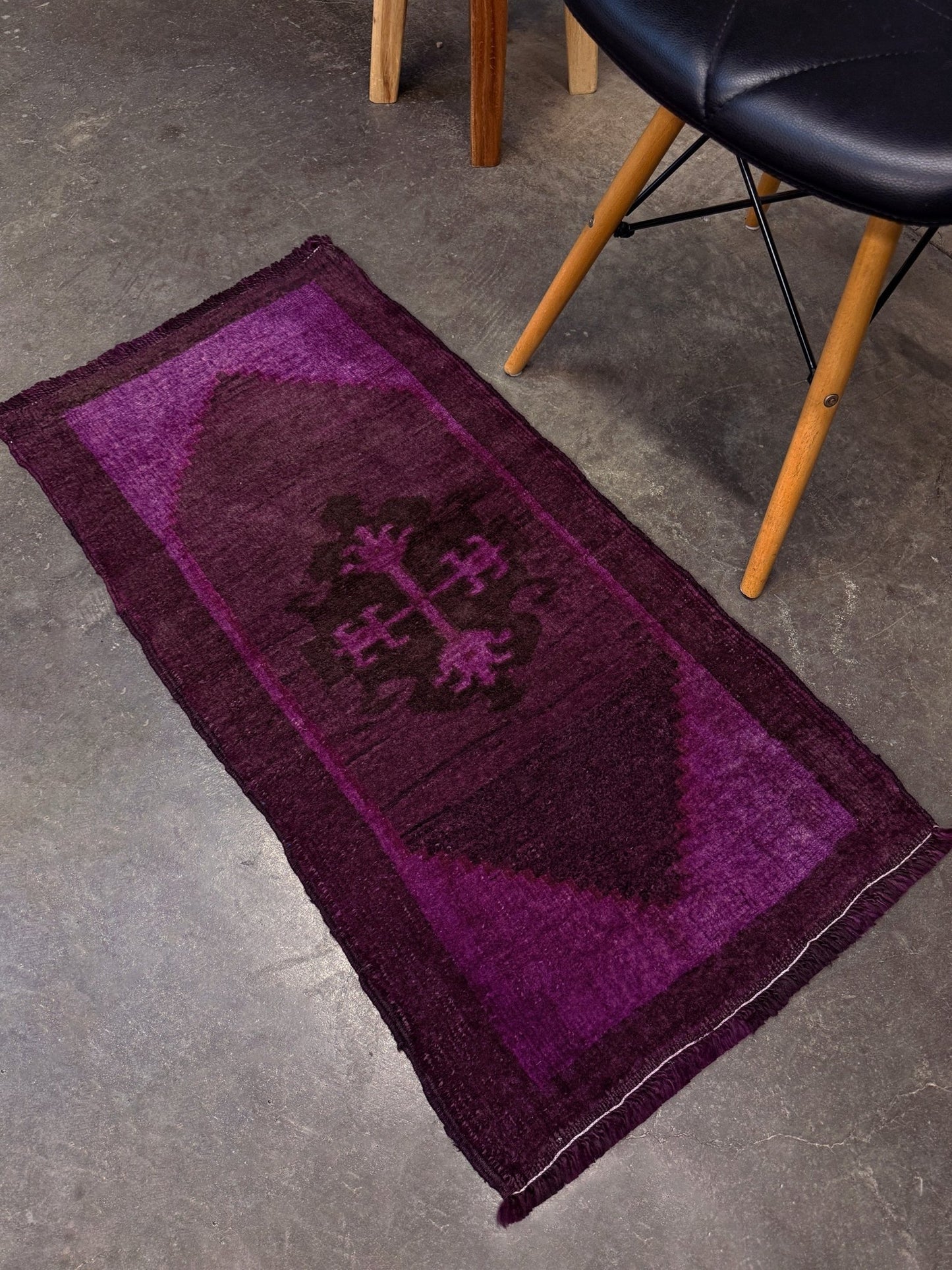 Vintage Turkish overdyed Yastik rug in plum, aubergine, and magenta purple with a shadowed black medallion. Hand-knotted wool, 19x38 inches. One-of-a-kind rug from Indigo Rugs in Burlingame, the best rug shop in the San Francisco Bay Area. Free shipping included.