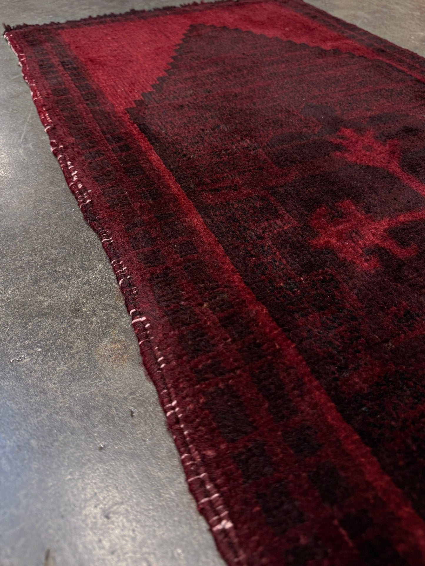 Vintage Turkish overdyed Yastik rug in ruby red tones with subtle shadowed motifs. Hand-knotted wool, 18x40 inches. Perfect for: Entryway, apartment foyers, beside the bed, kitchen sink areas, bathroom vanity spots, layered under décor piecesOne-of-a-kind rug from Indigo Rugs in Burlingame, the best rug shop in the San Francisco Bay Area. Free shipping included.