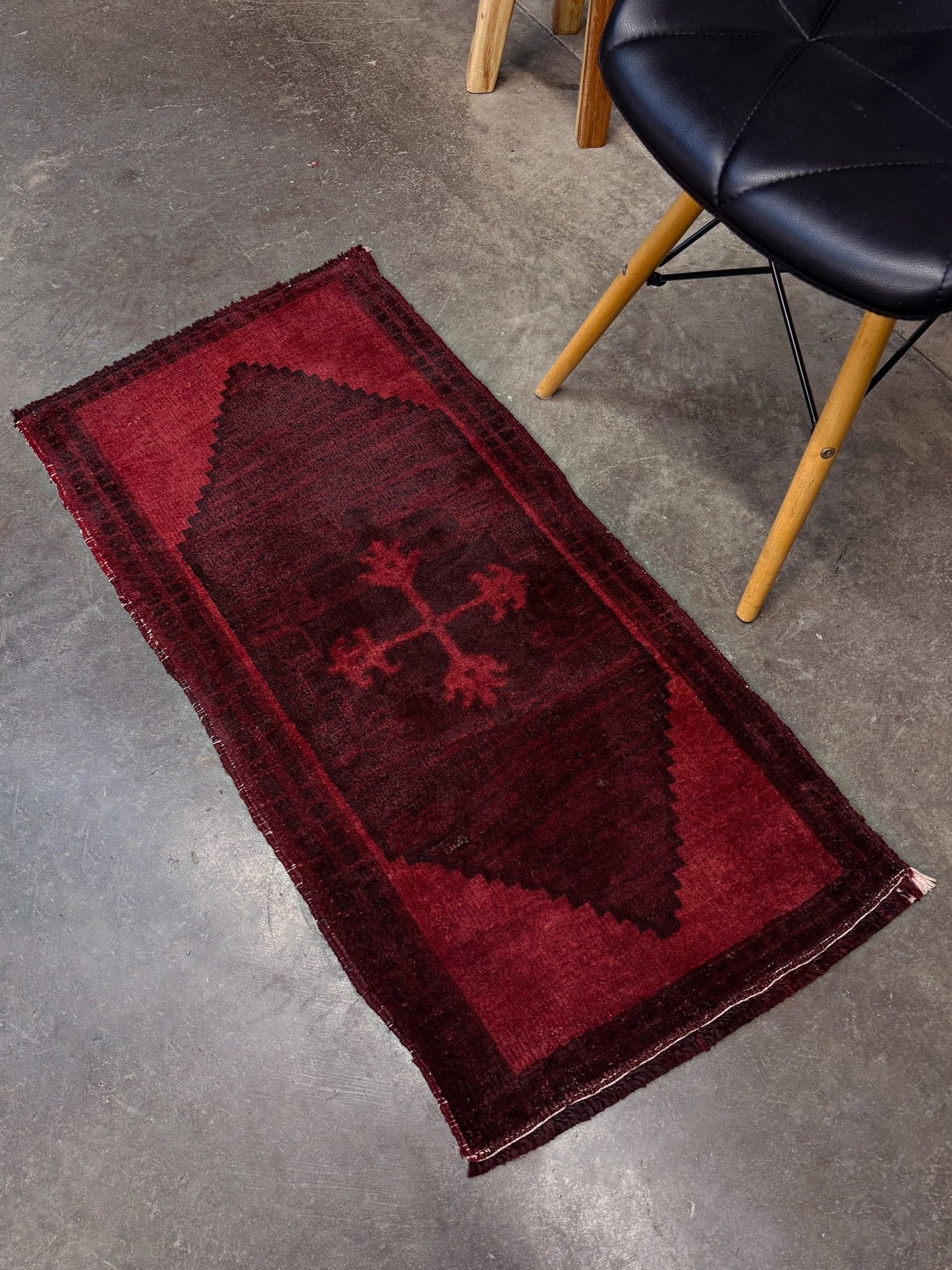 Vintage Turkish overdyed Yastik rug in ruby red tones with subtle shadowed motifs. Hand-knotted wool, 18x40 inches. Perfect for: Entryway, apartment foyers, beside the bed, kitchen sink areas, bathroom vanity spots, layered under décor piecesOne-of-a-kind rug from Indigo Rugs in Burlingame, the best rug shop in the San Francisco Bay Area. Free shipping included.
